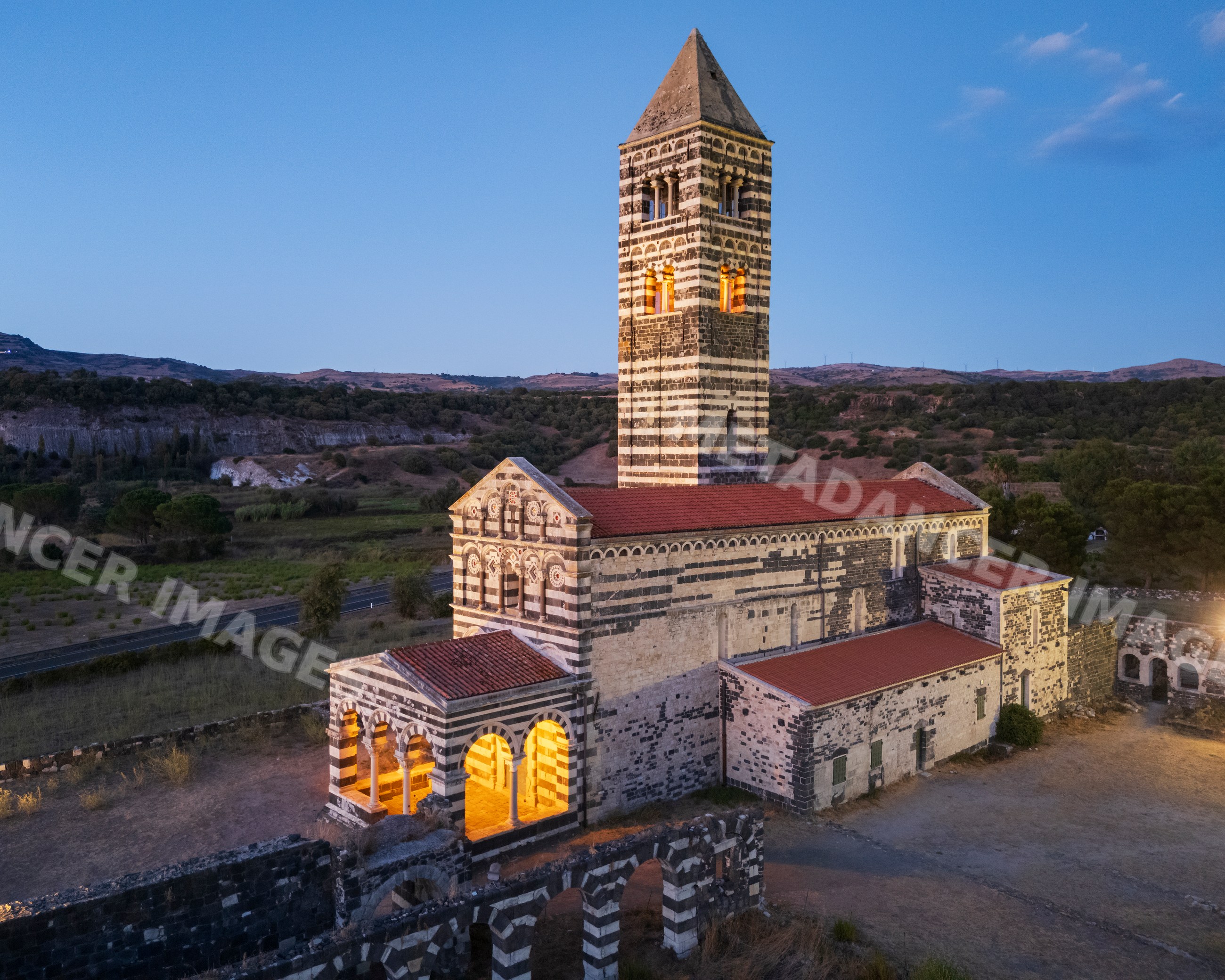 Romanesque church tower with lit interior at dusk in sardinia, italy