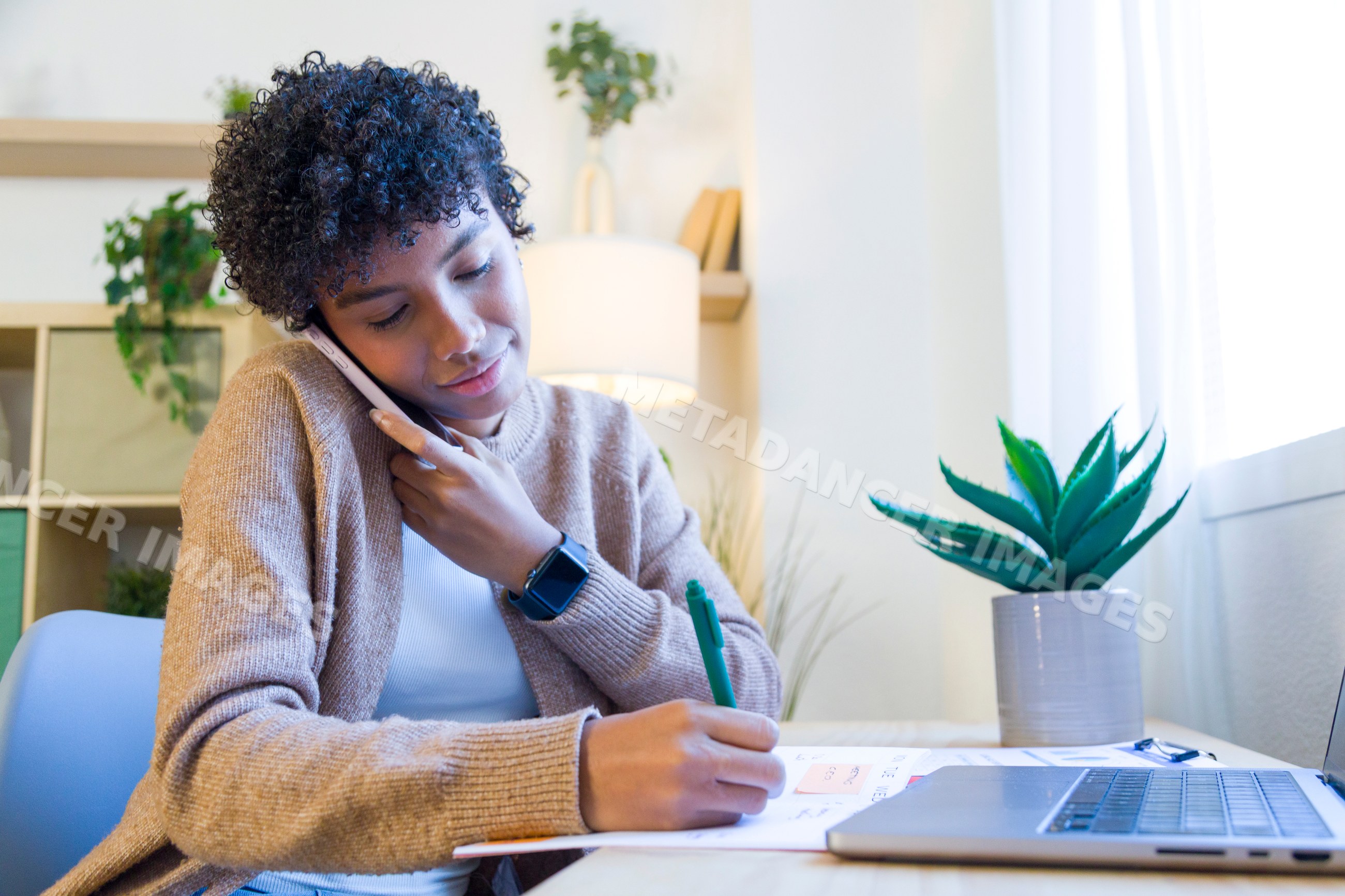 African American woman multitasks on phone call and note taking