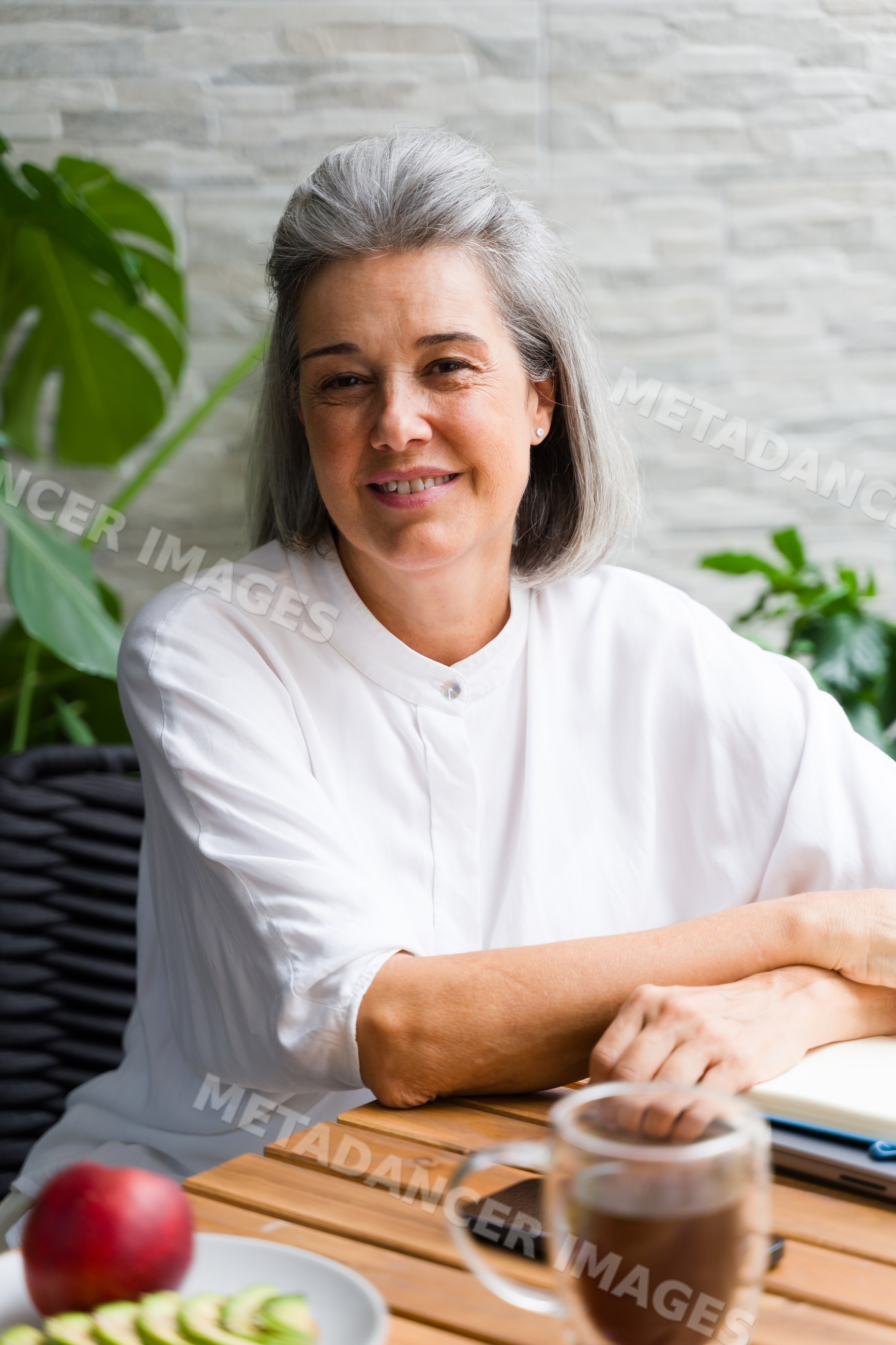 Middle-aged white woman sitting at a table with coffee and fruit