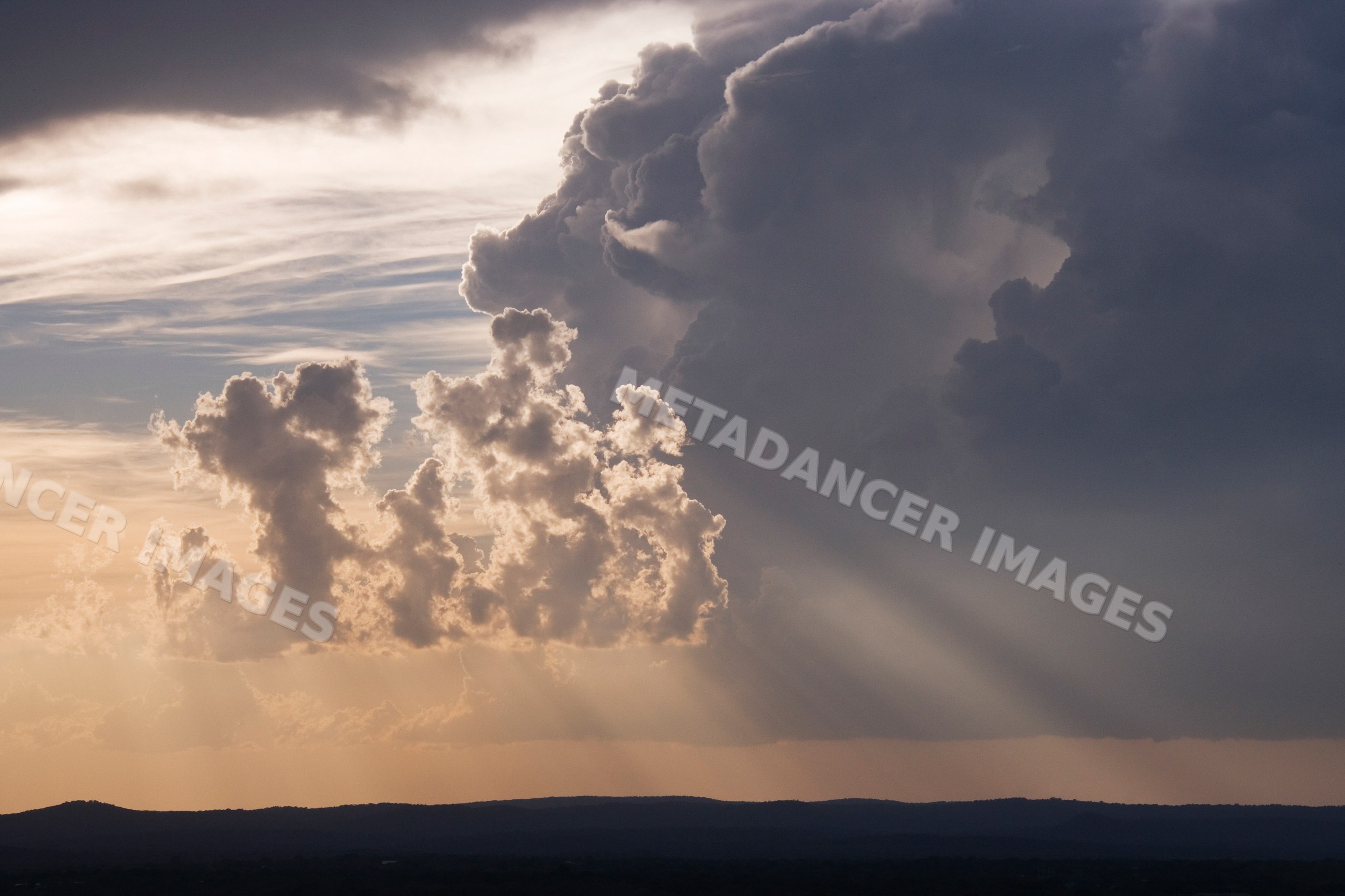 Storm clouds with sun rays over texas hills
