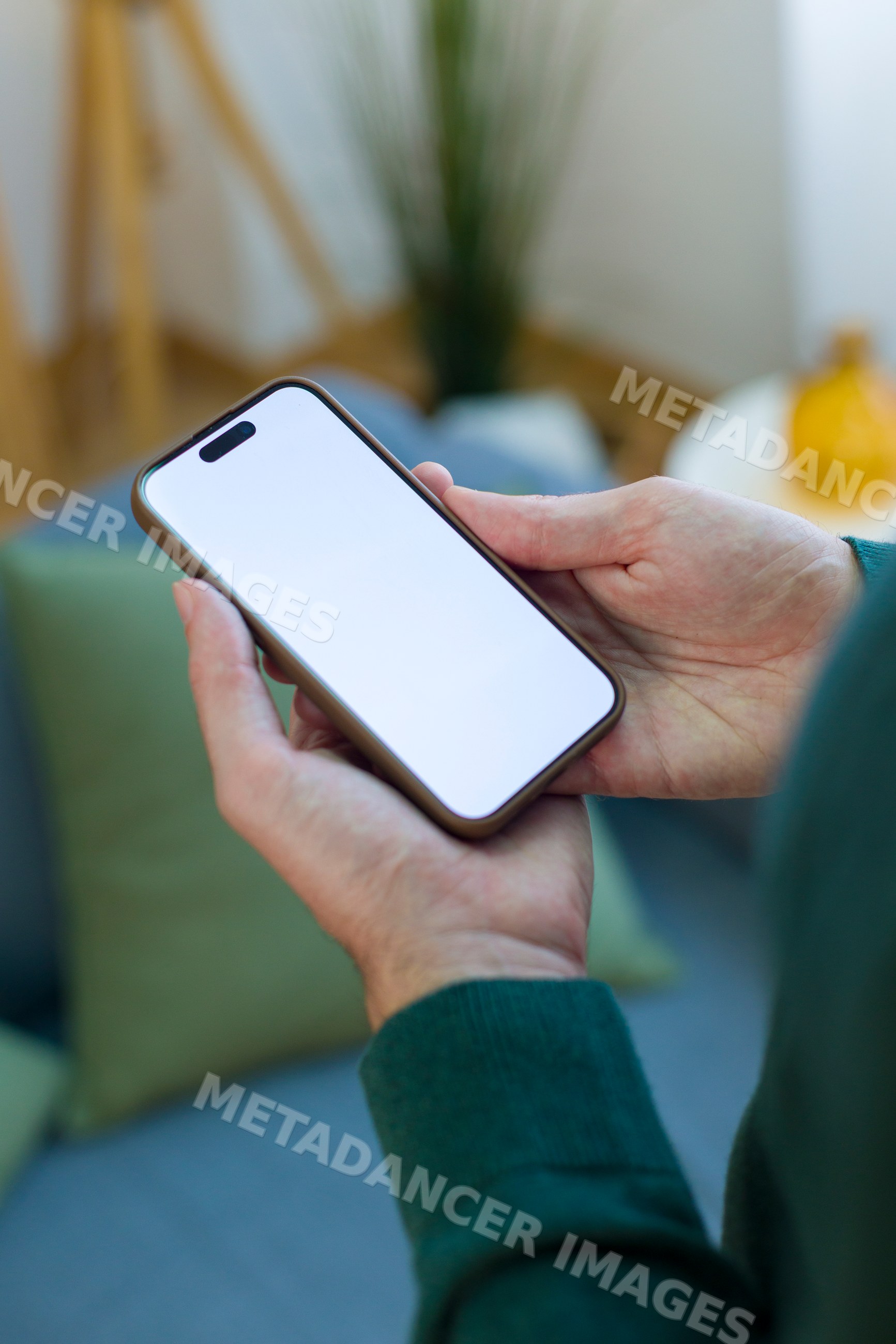 White person holding smartphone with blank screen indoors