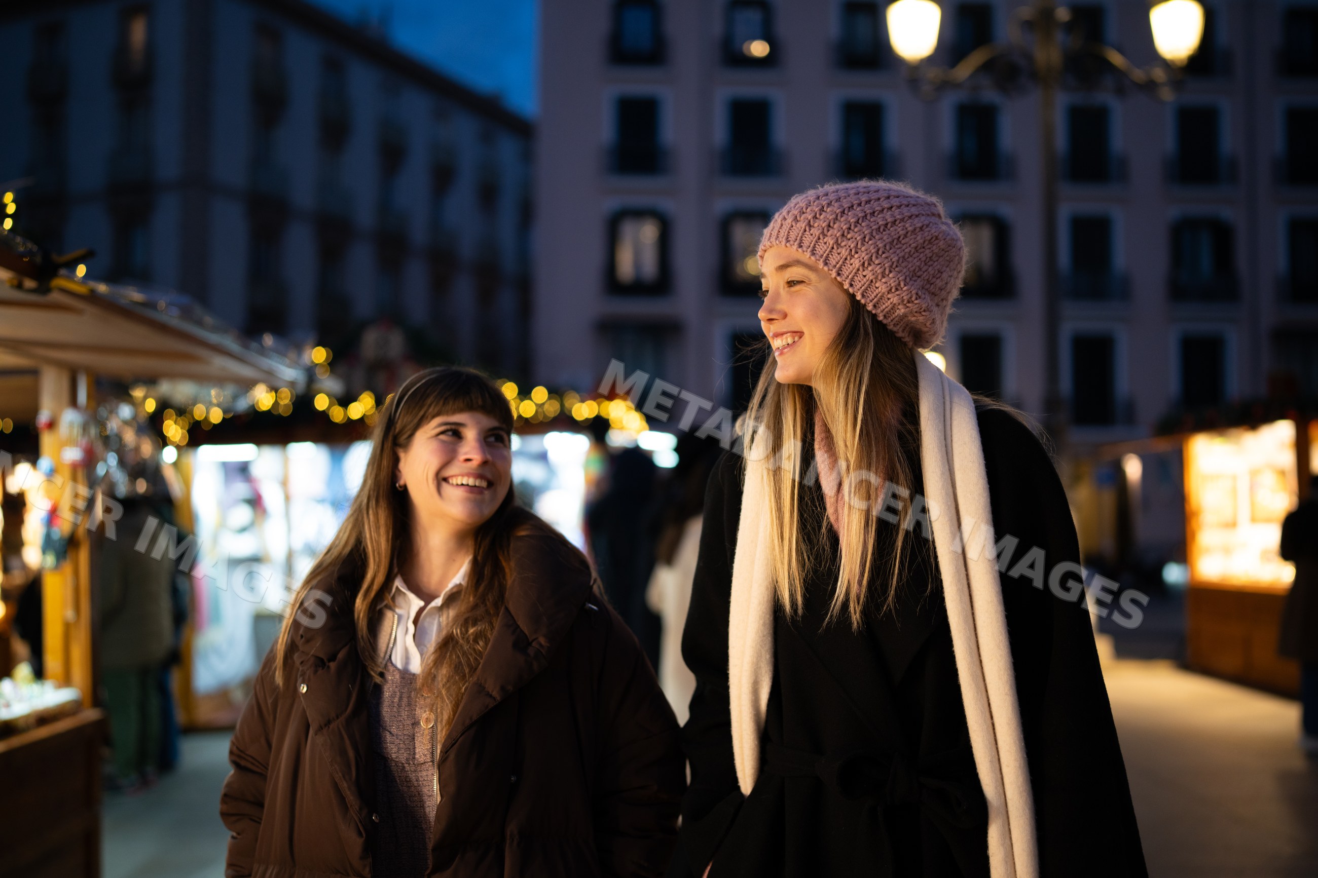 Two white women smiling at a christmas market at night in Madrid