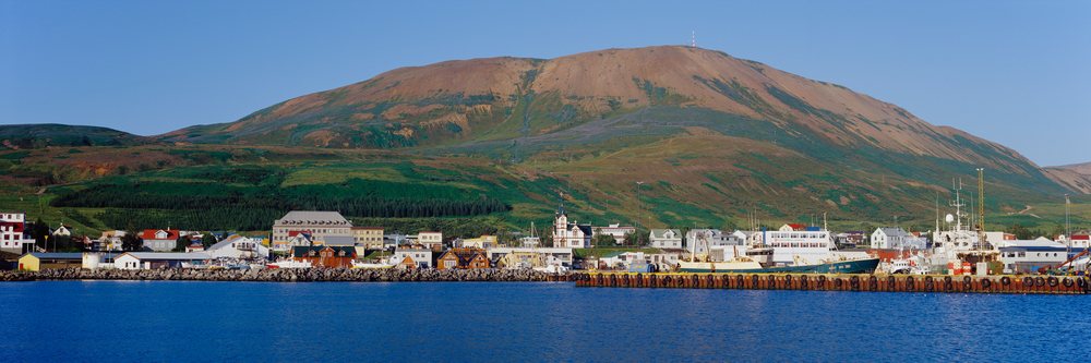 Fishing boats docked in small harbor by mountainous coastal town