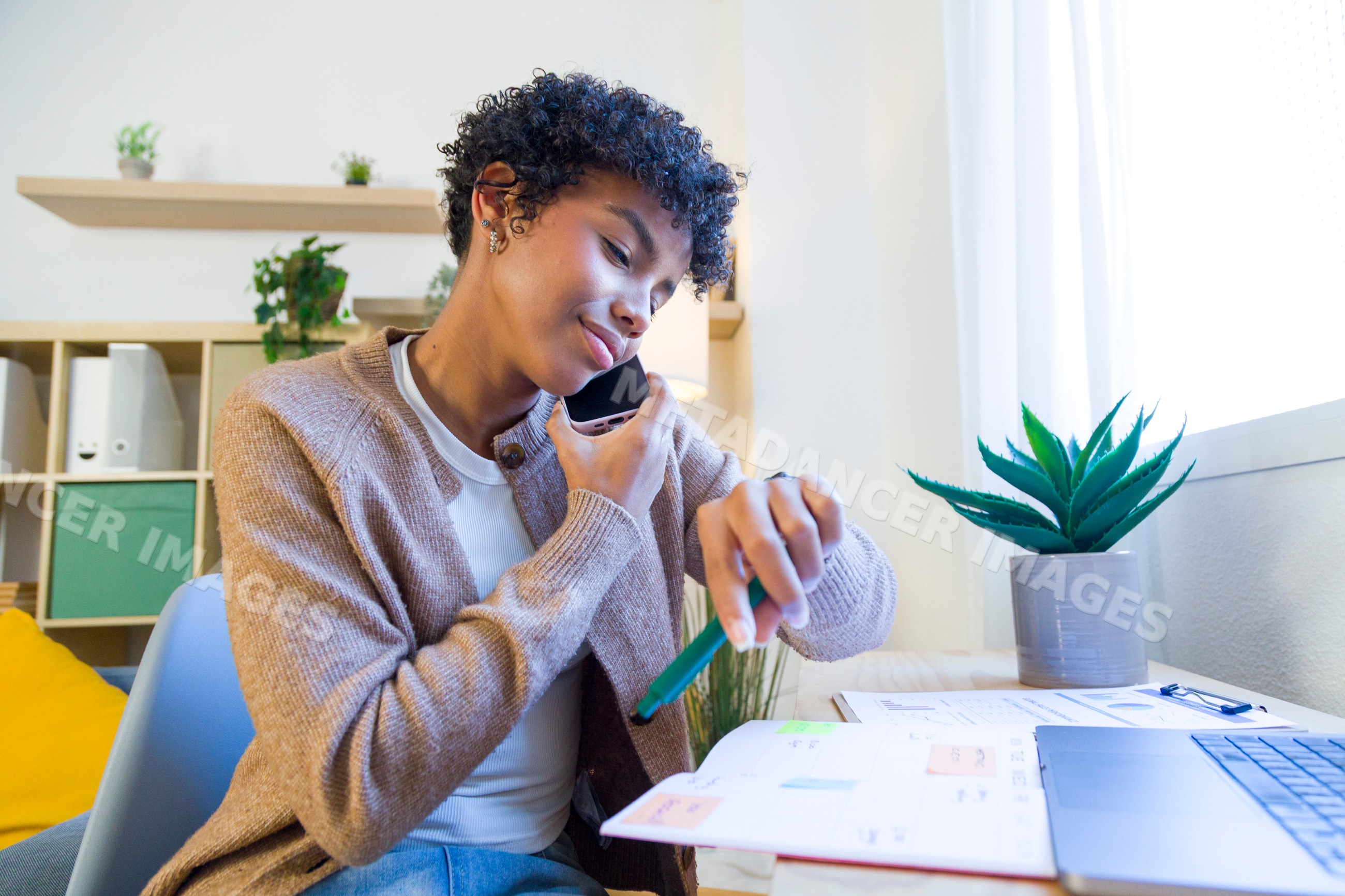 African American woman multitasking in home office checking time