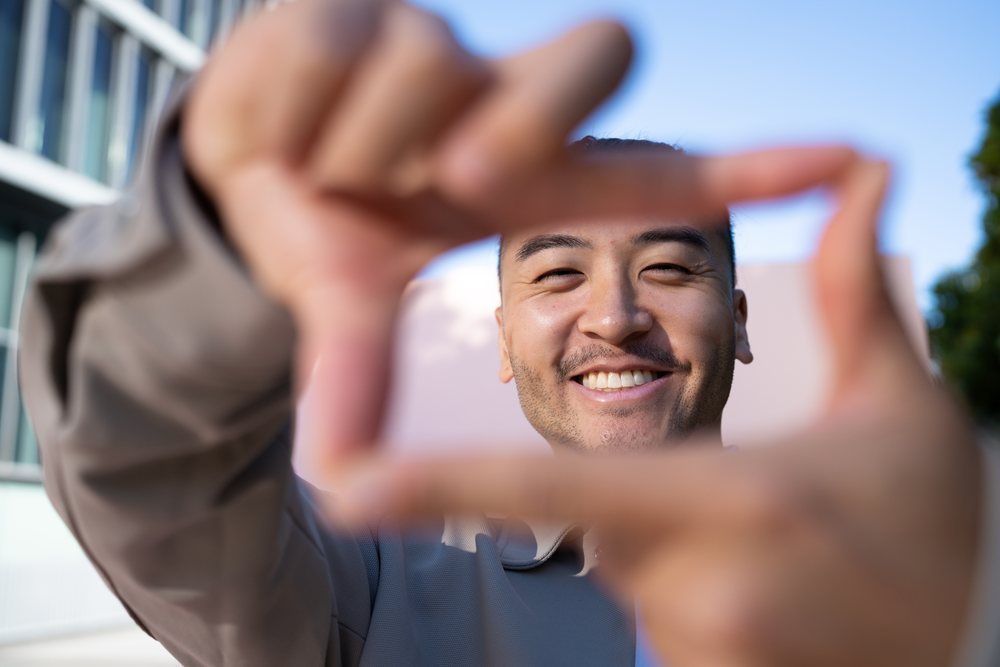 Man smiling framing gesture outdoors under blue sky