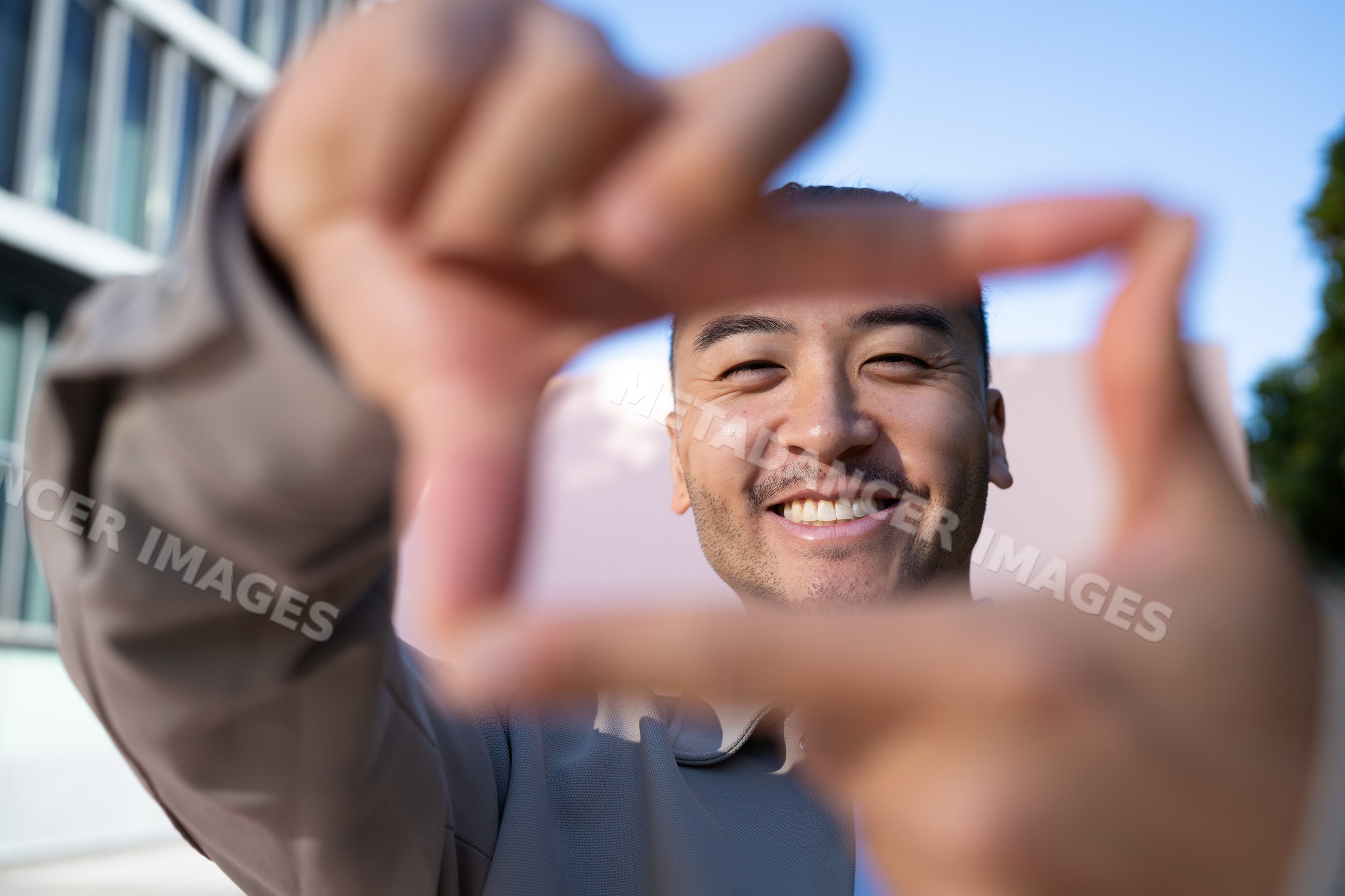 Man smiling framing gesture outdoors under blue sky