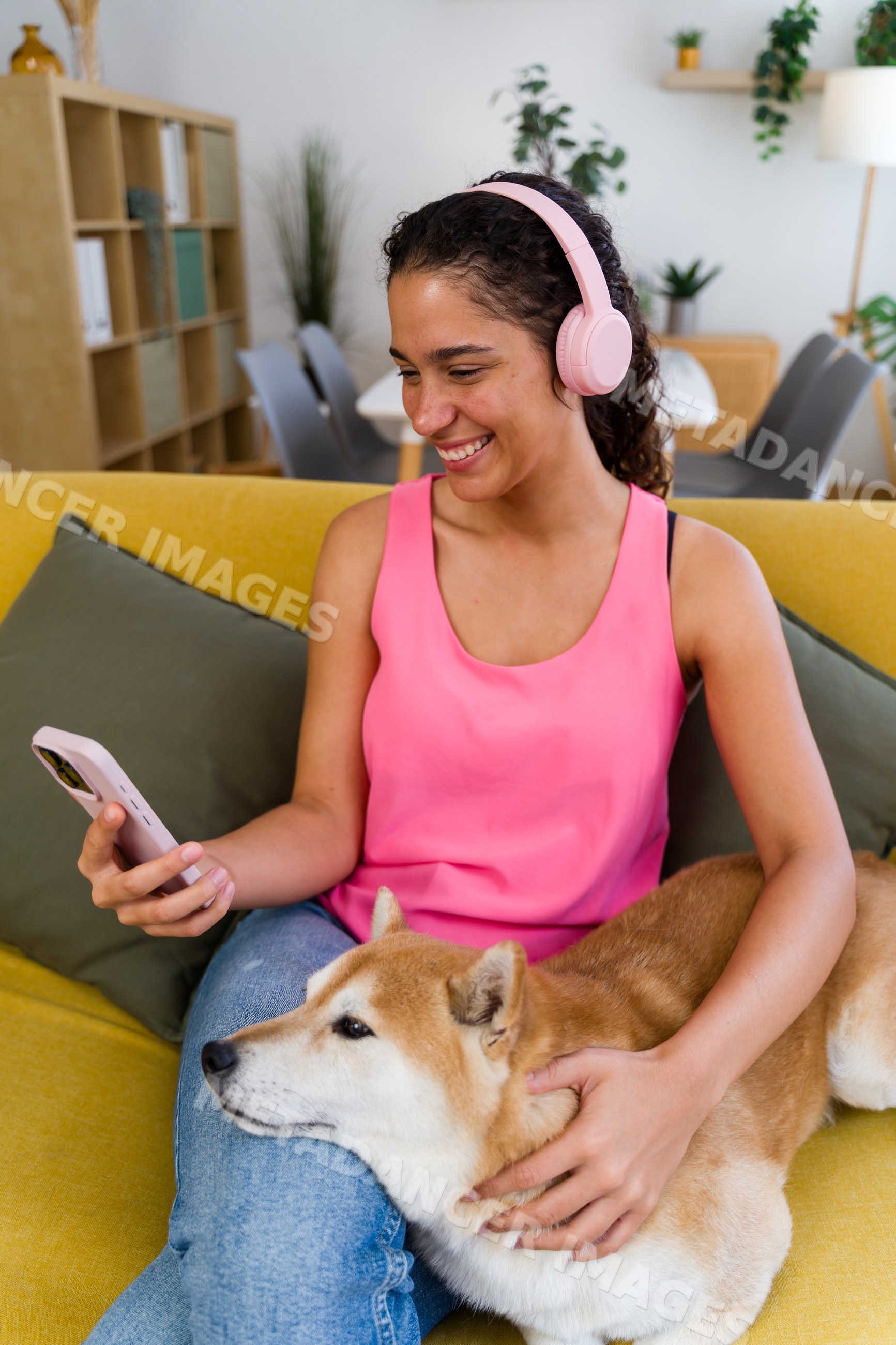 A Hispanic woman with headphones petting her dog