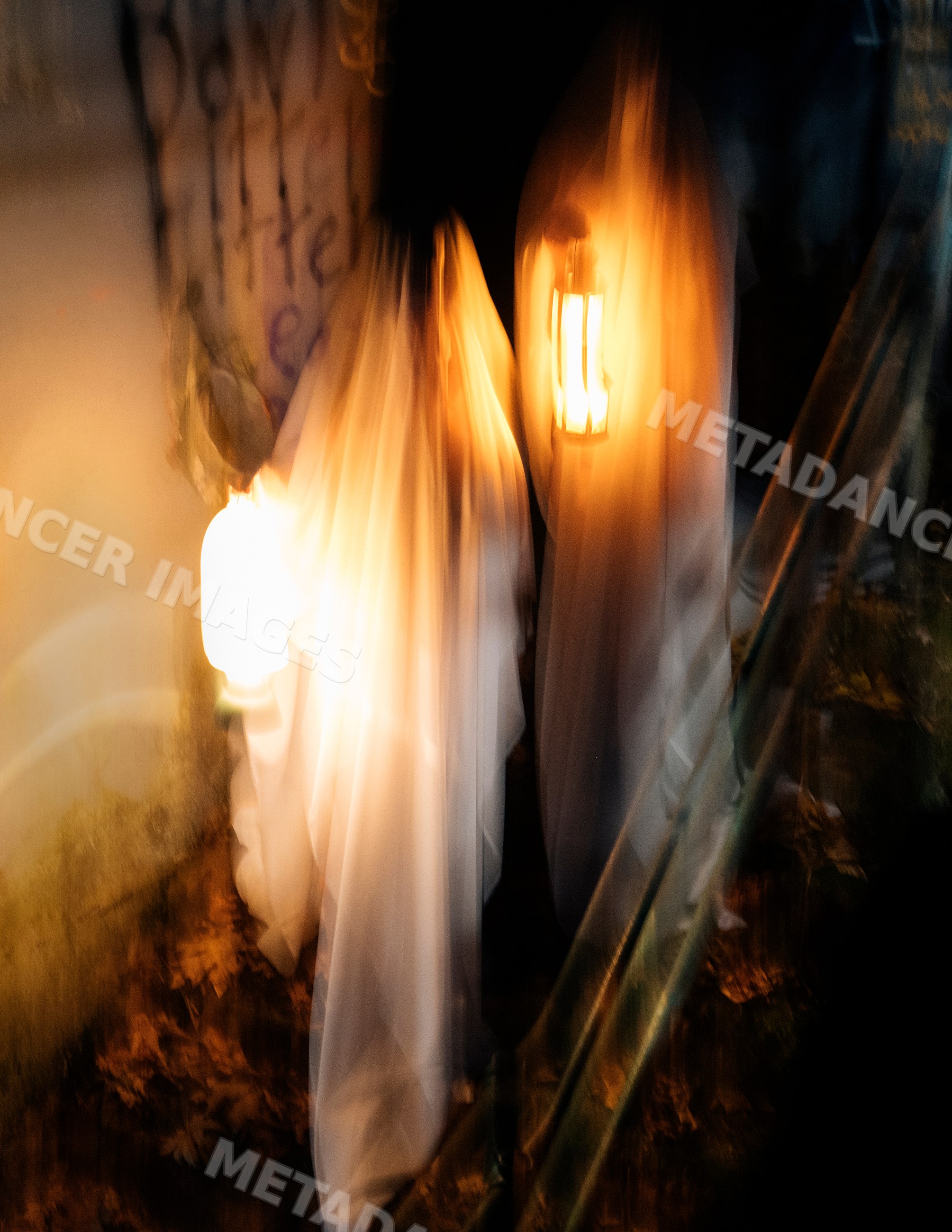 Ghost figures carrying lanterns at night during halloween