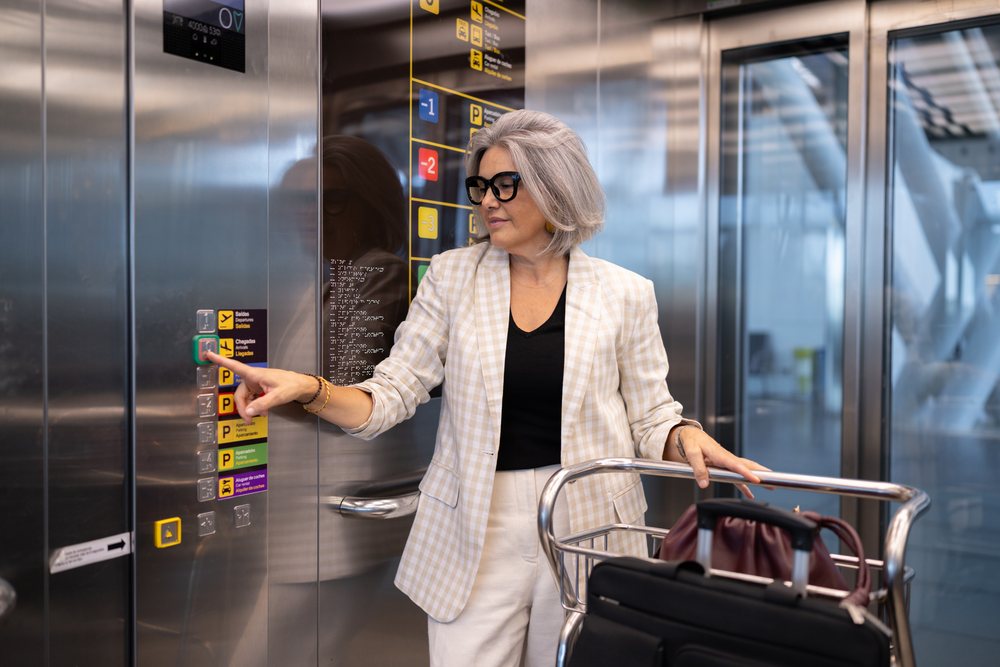 White woman traveler pushing elevator button in a modern airport