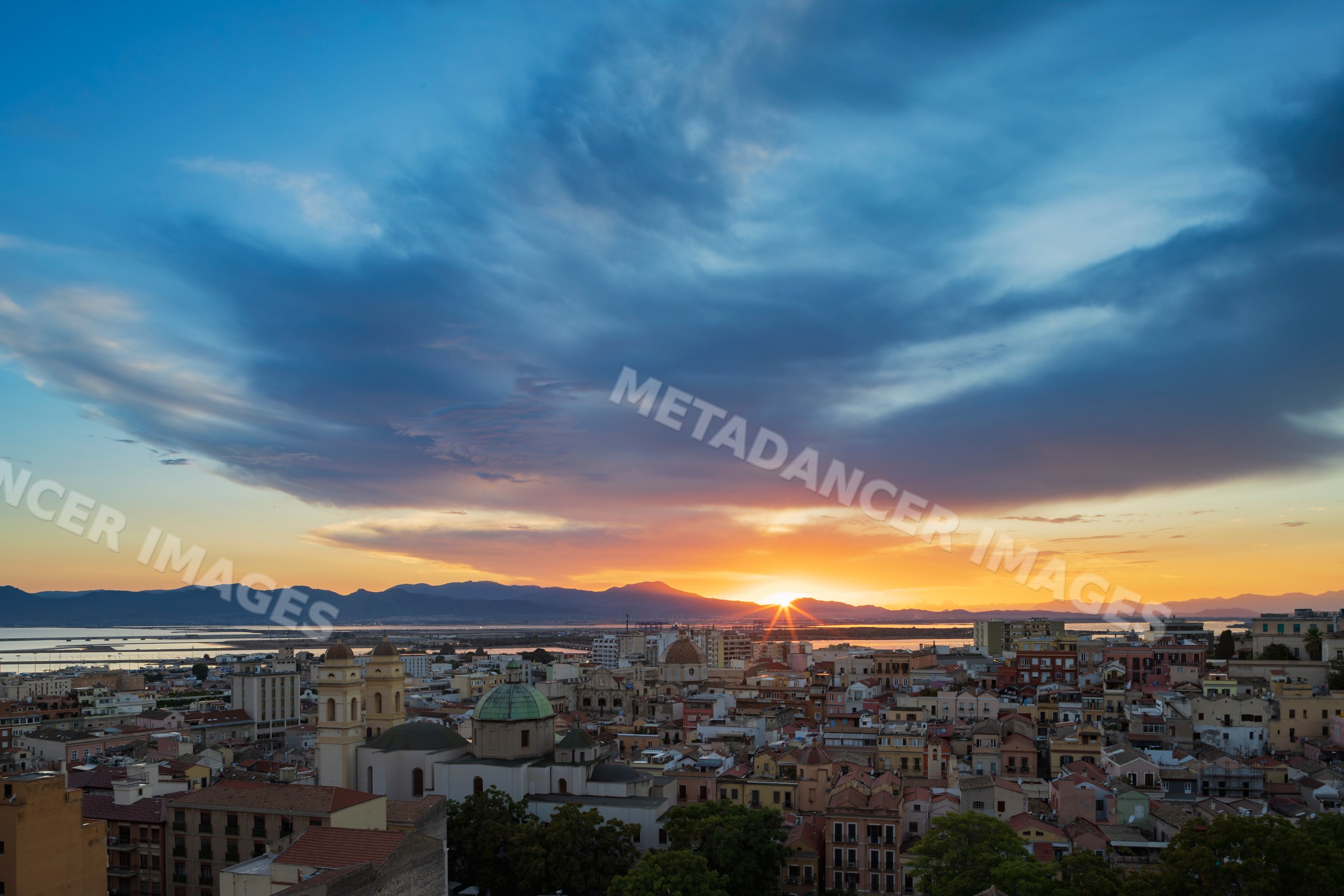 Cagliari city skyline at Sunset with glowing sun and clouds