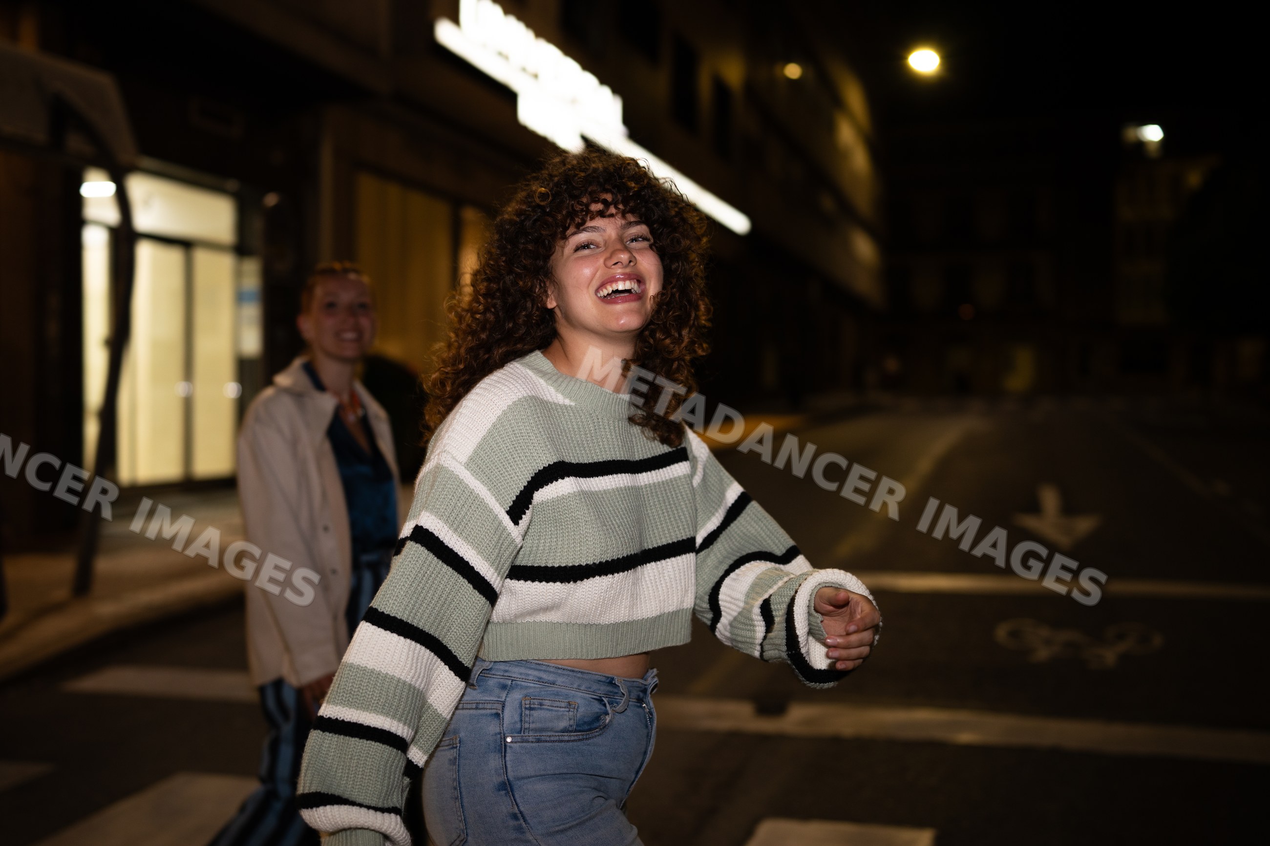 White woman laughing and walking with friend on a nighttime city