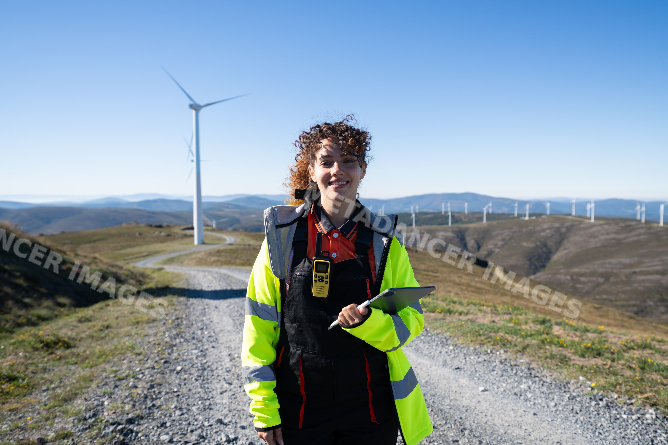 White woman engineer inspecting wind turbines at mountain wind farm