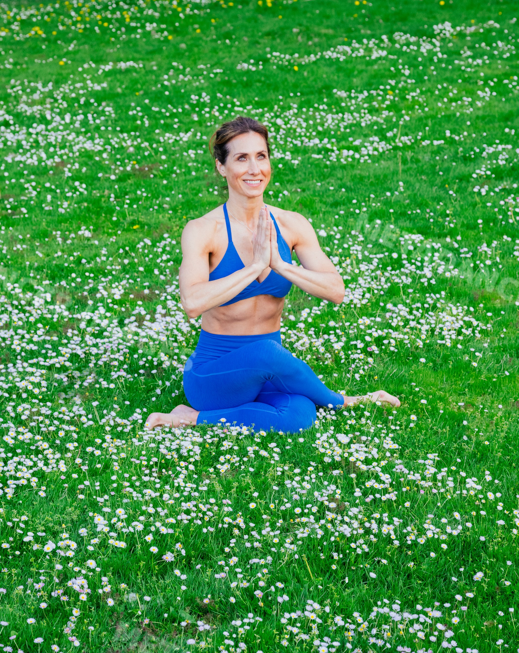 White woman practicing yoga meditation in wildflower field outdoors