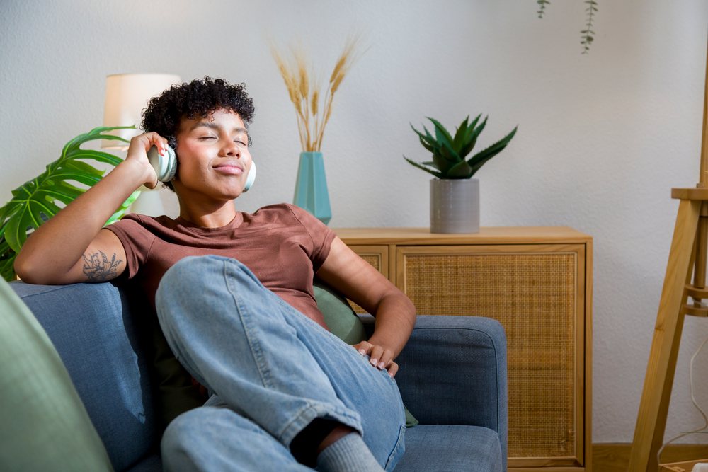 Young African American woman relaxing on sofa listening to music