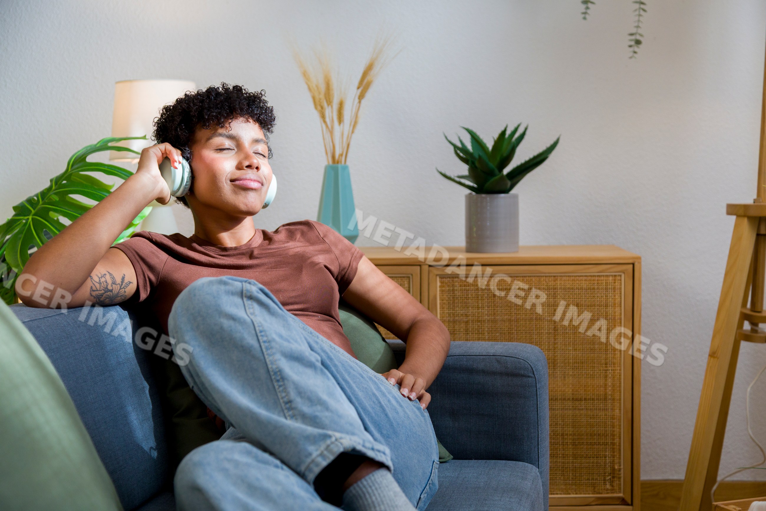 Young African American woman relaxing on sofa listening to music