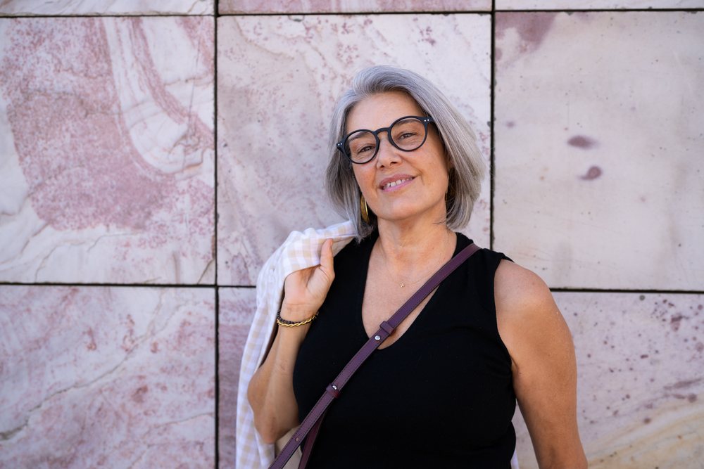 Portrait of a confident white woman with gray hair and glasses against