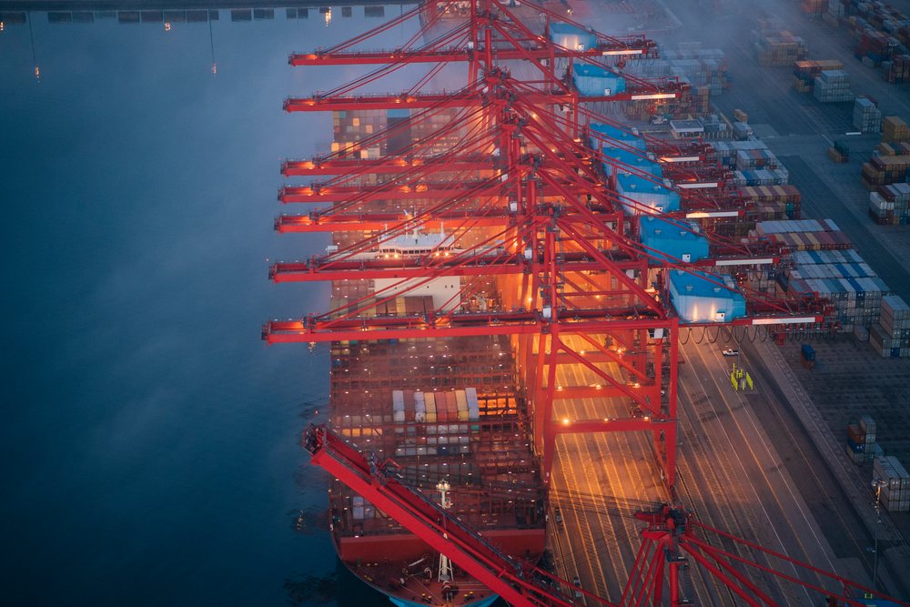 A container ship is loaded with cargo at a busy port in a beach
