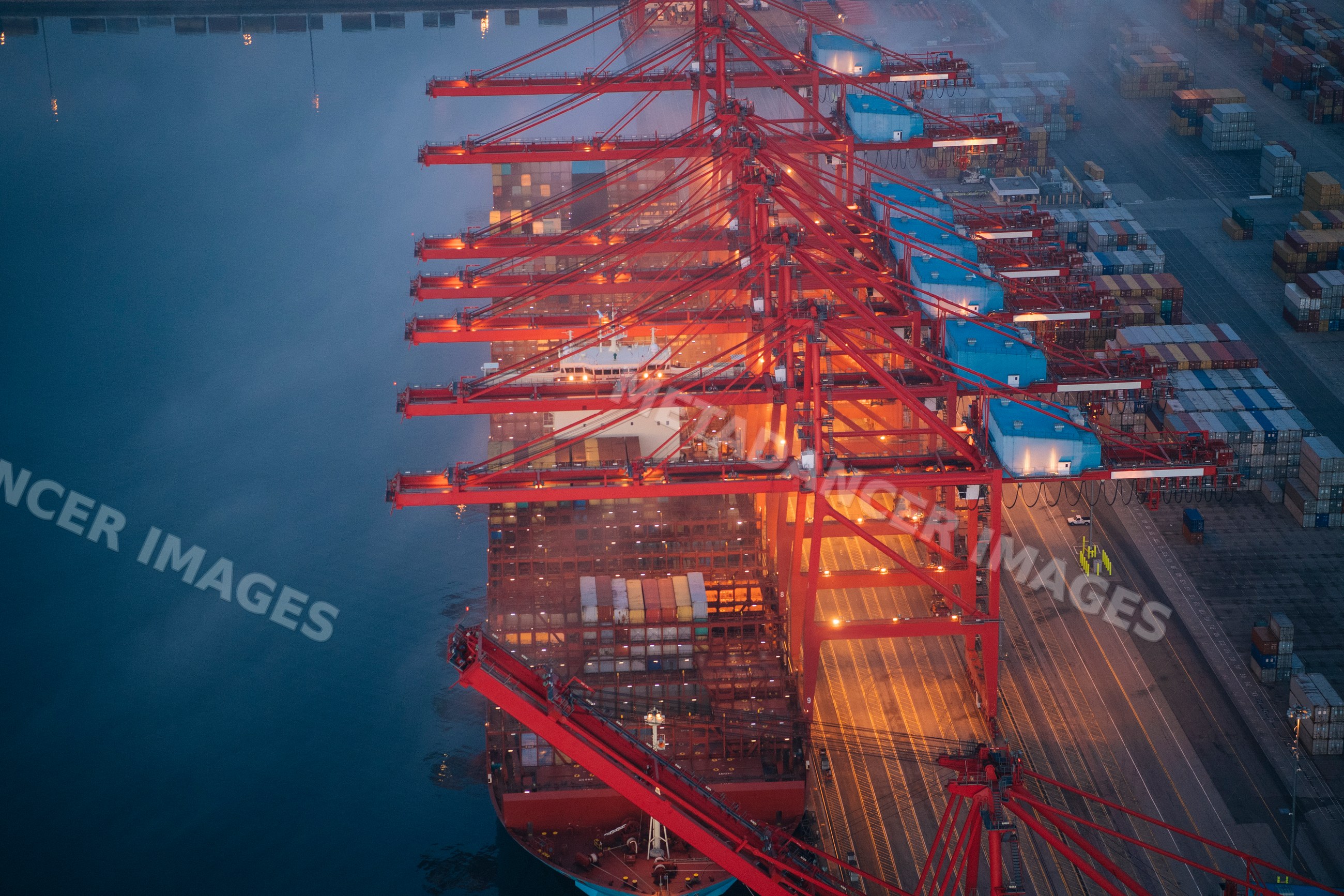 A container ship is loaded with cargo at a busy port in a beach