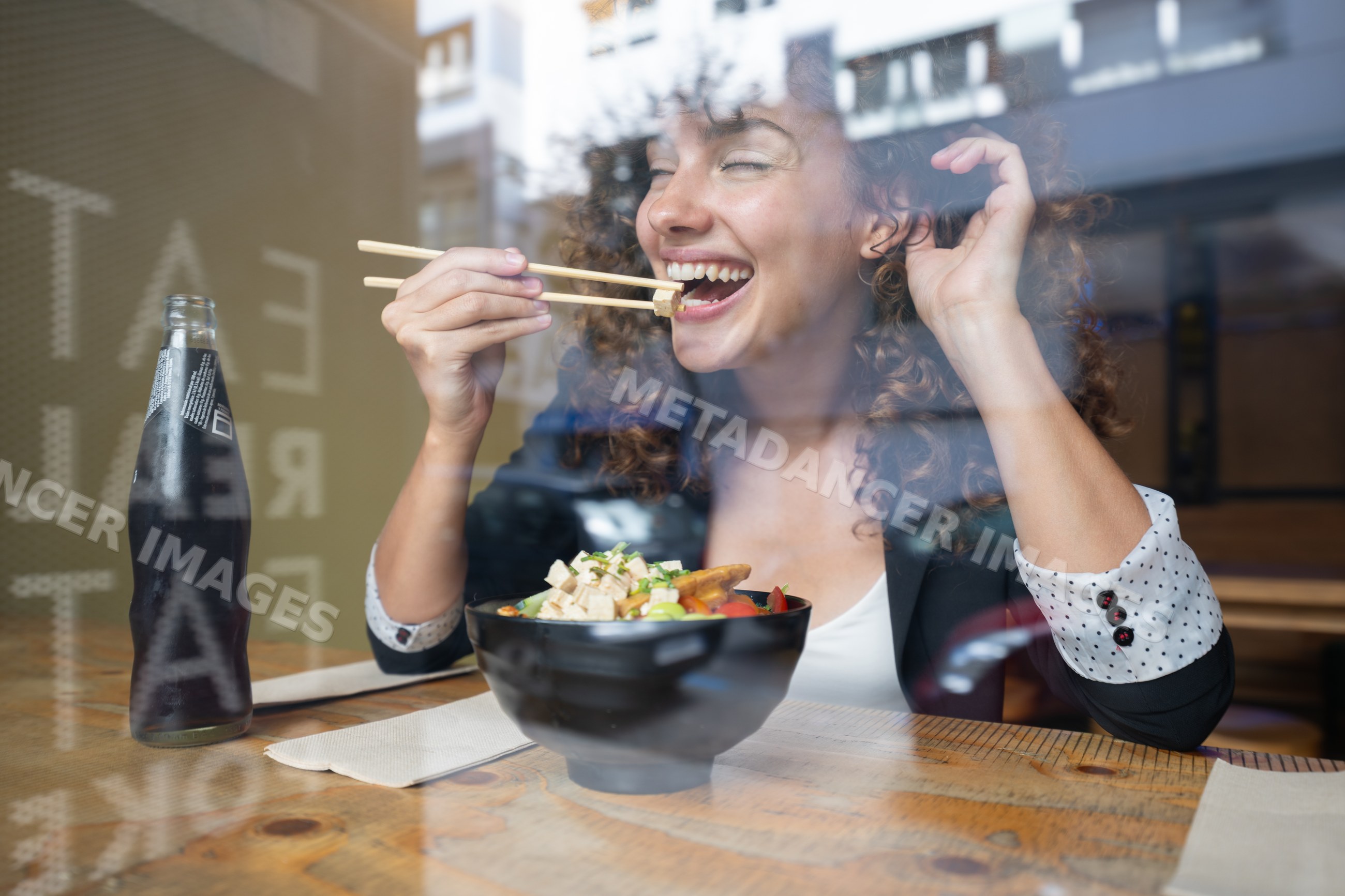 White woman enjoying meal with chopsticks inside restaurant in Spain
