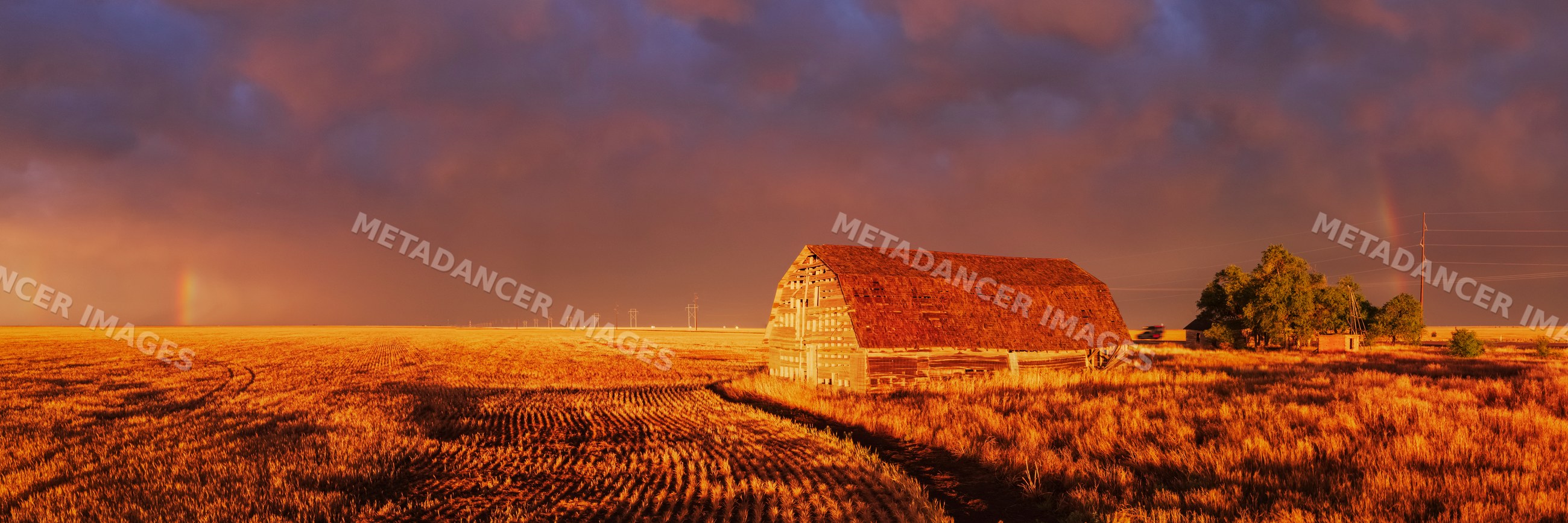 Old barn at Sunset with Rainbow over rural field