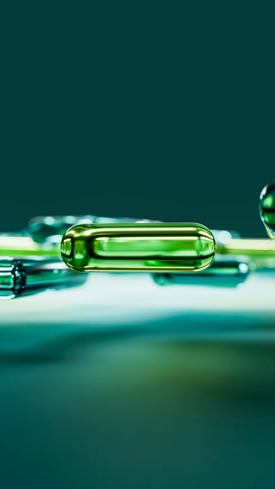 Close-up of green softgel capsule with reflective surface