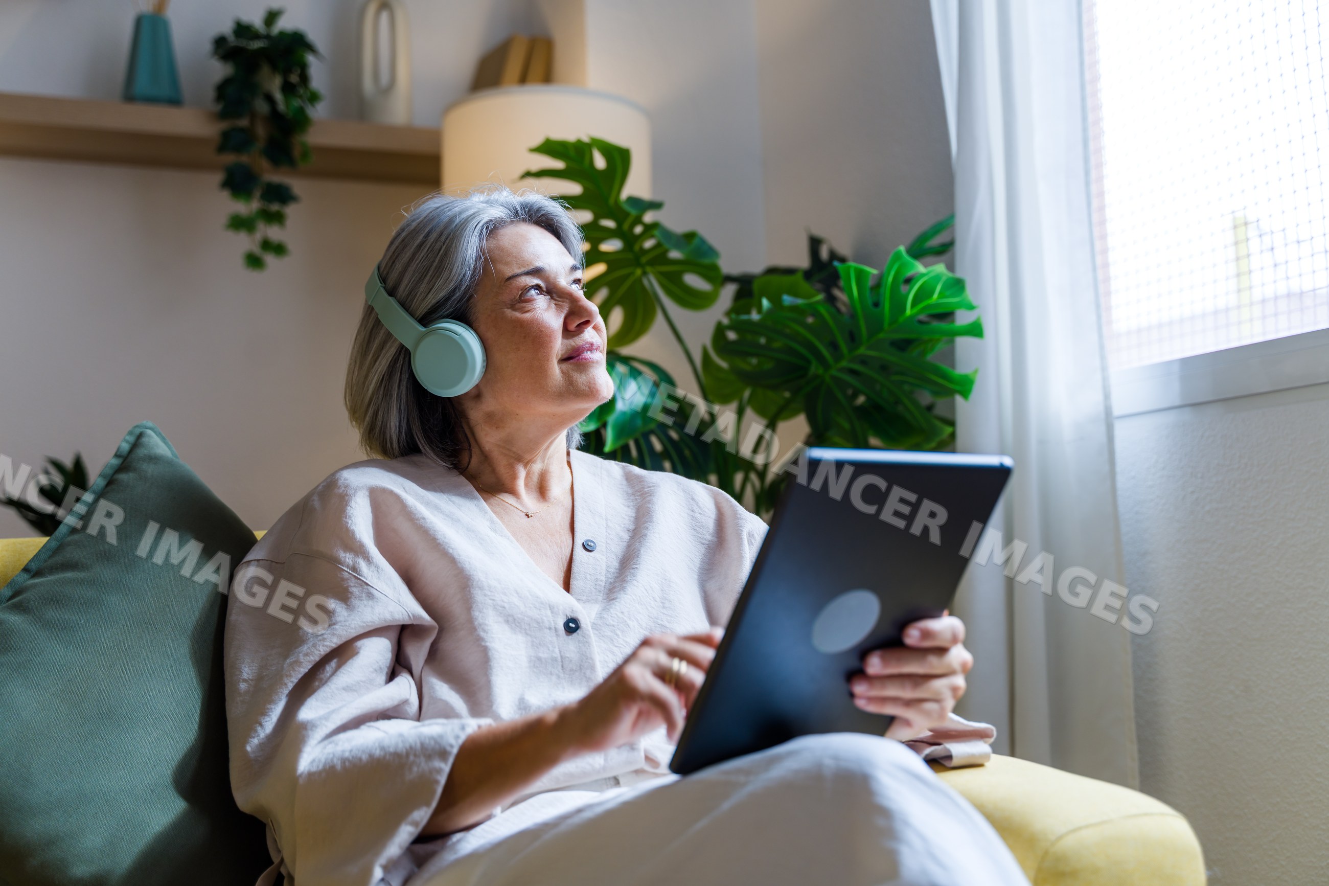 White woman wearing headphones using tablet at home in Spain
