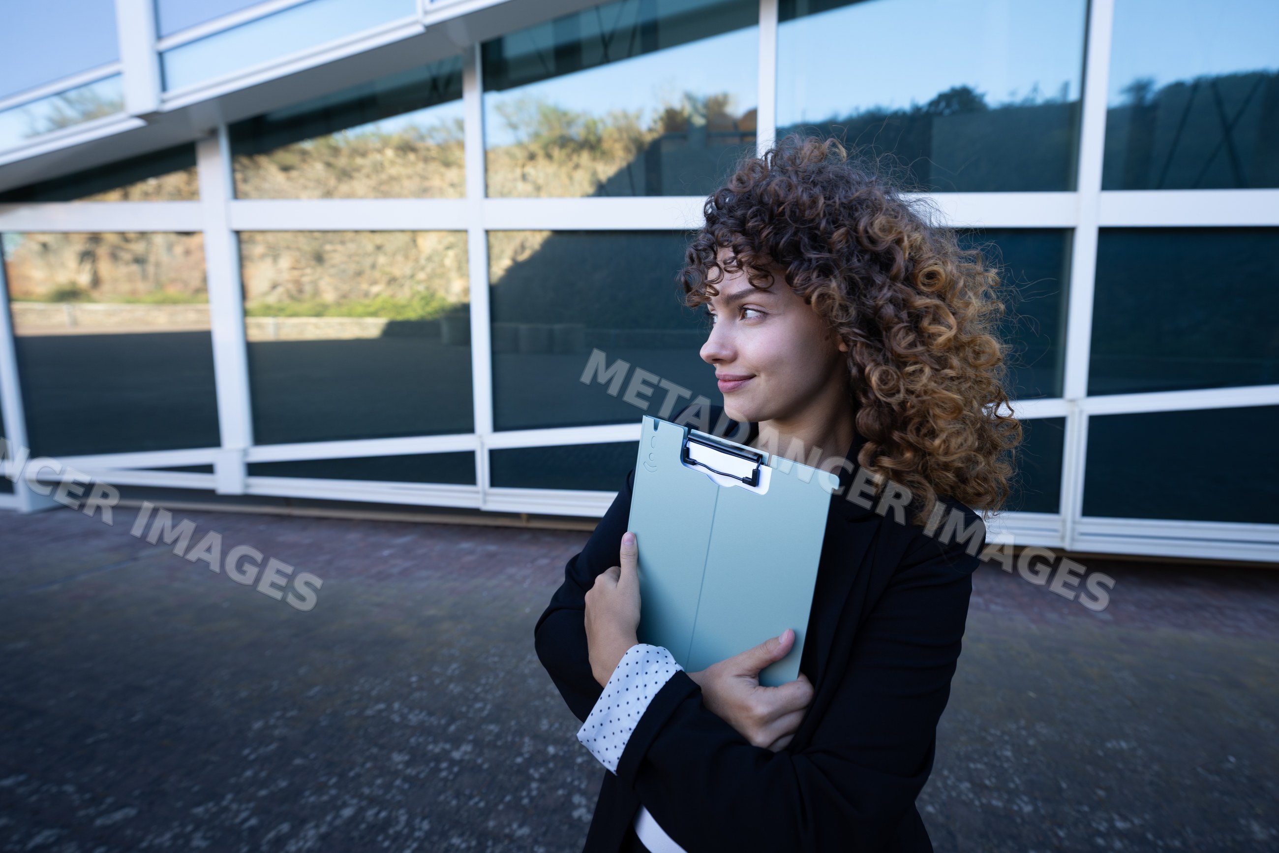 Businesswoman holding folder outside modern office building