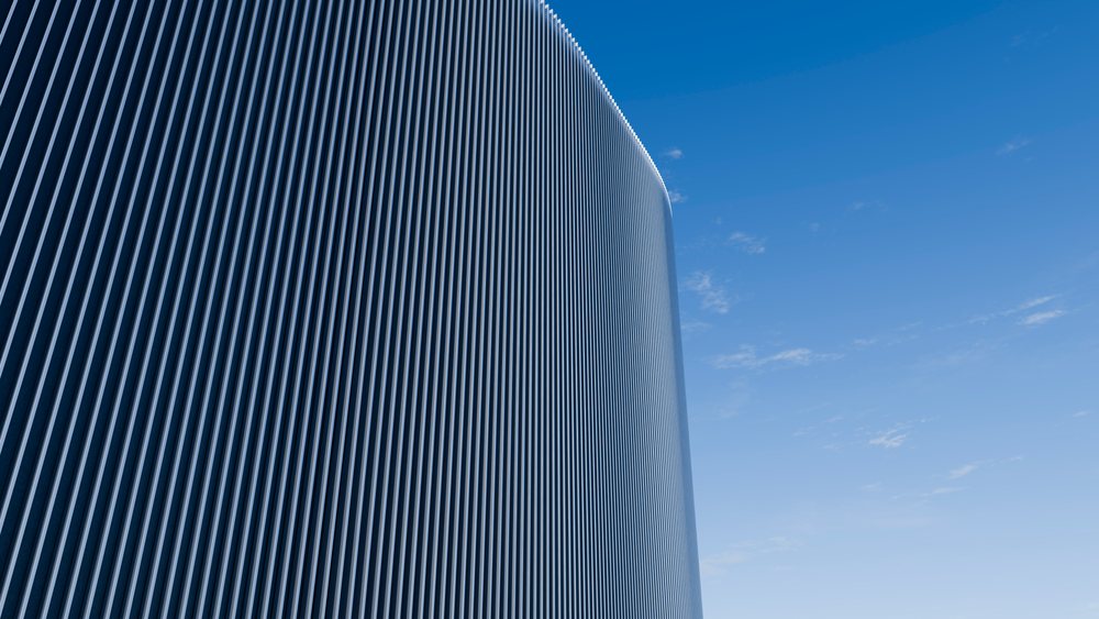 Curved modern building with vertical lines facade under blue sky