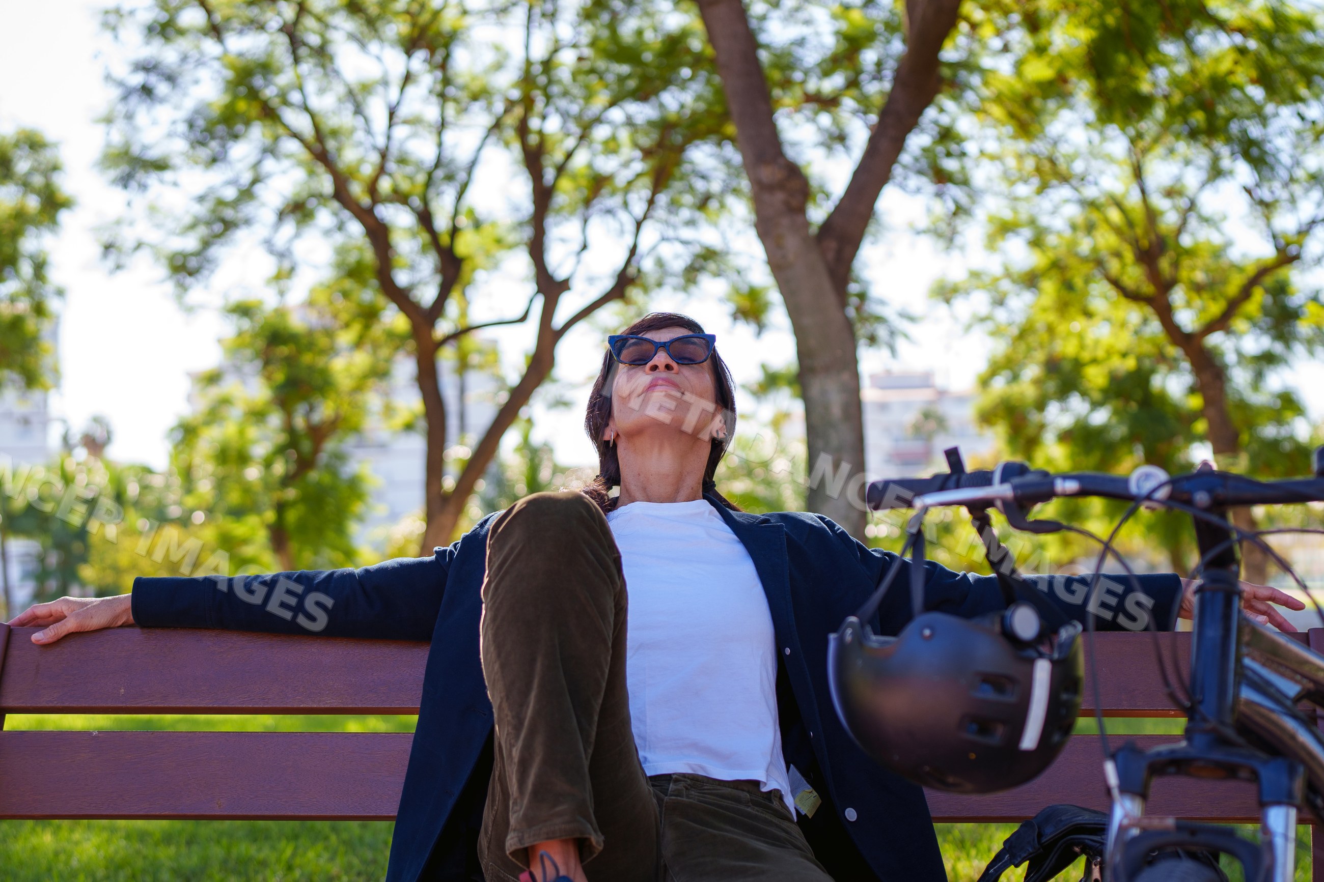 Hispanic woman relaxing on bench with bicycle in Málaga park