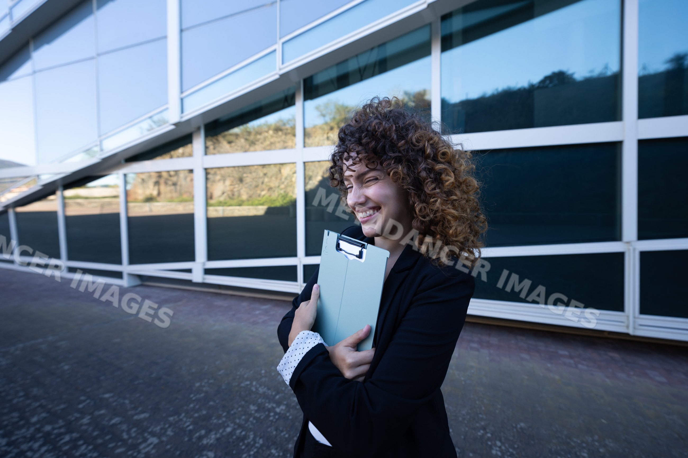Businesswoman holding clipboard outside modern building