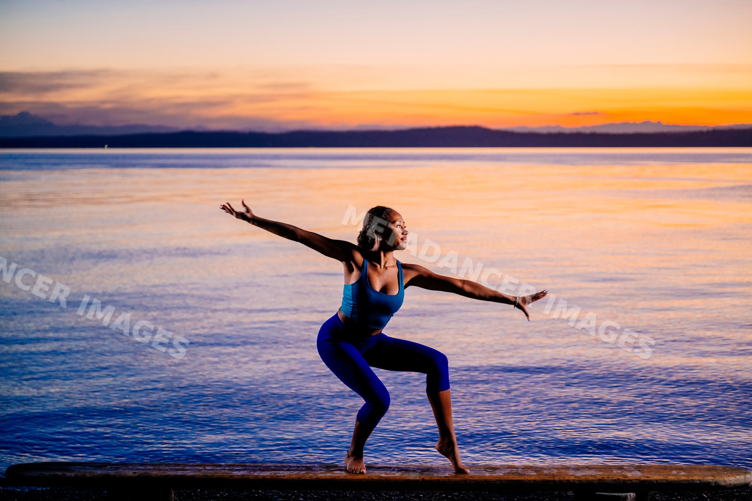 Hispanic woman balancing in acrobatic yoga pose outdoors at sunset