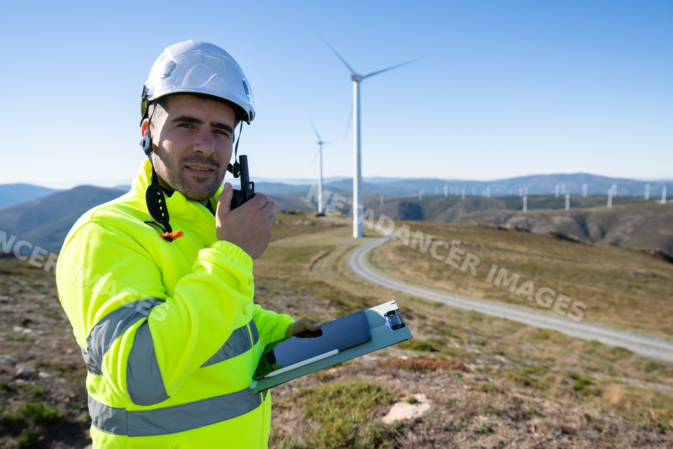 Engineer using radio walkie talkie at wind farm in Galicia Spain