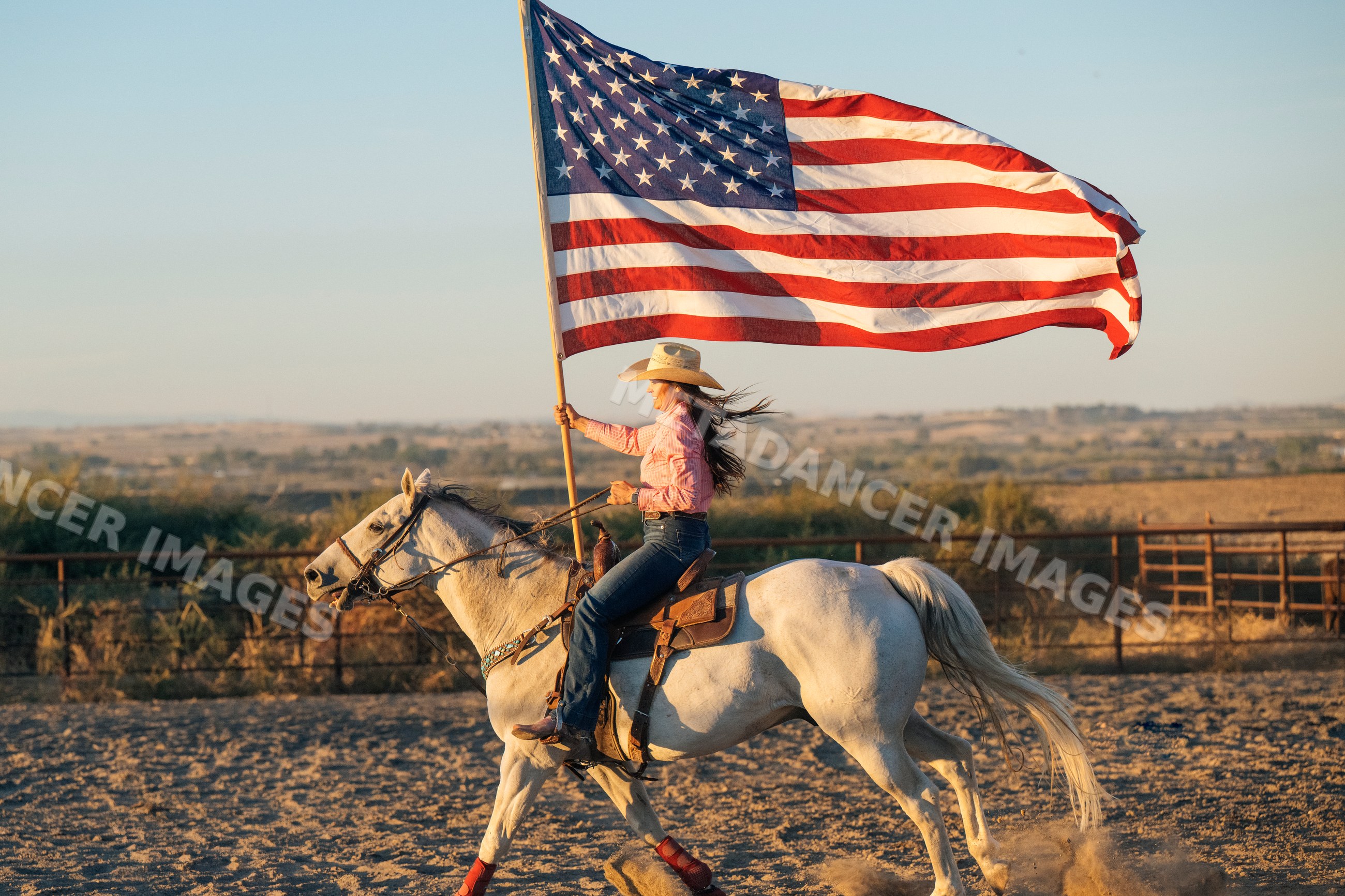 White woman riding horse with american flag in Southwest USA desert