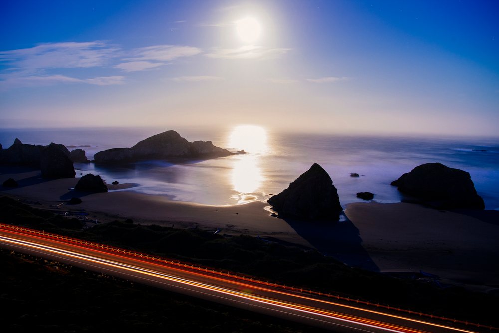 Ocean coast with rock formations and light trails on road