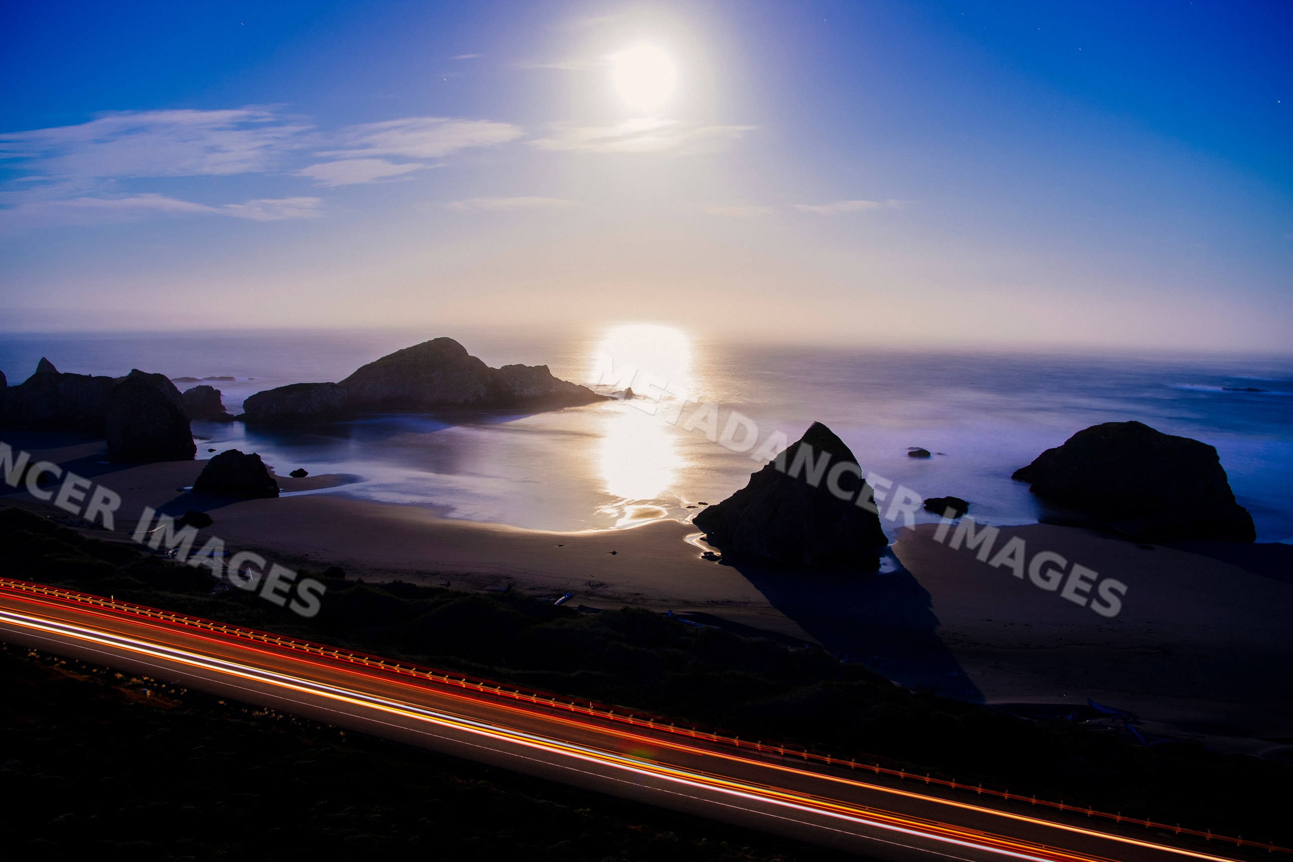 Ocean coast with rock formations and light trails on road