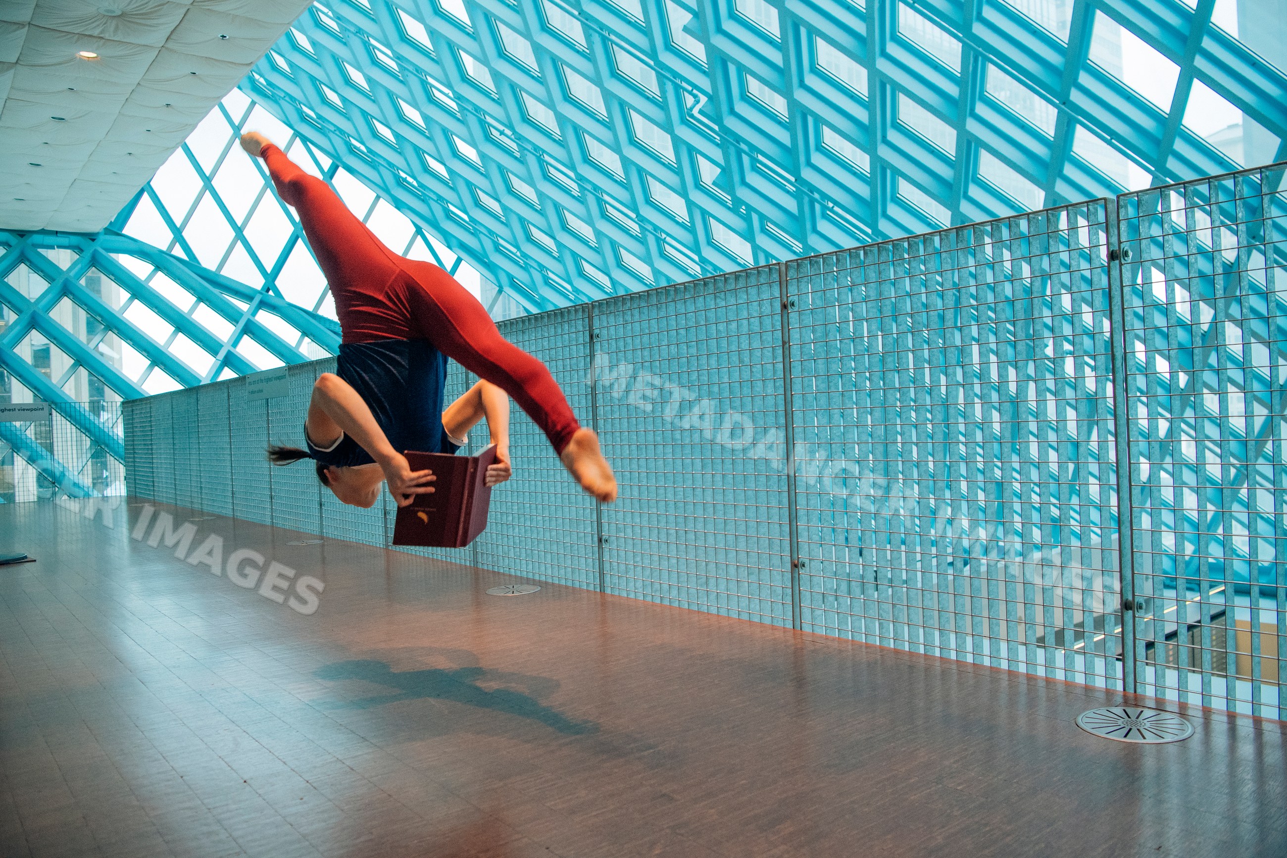 Woman jumping and reading a book inside the Seattle public library