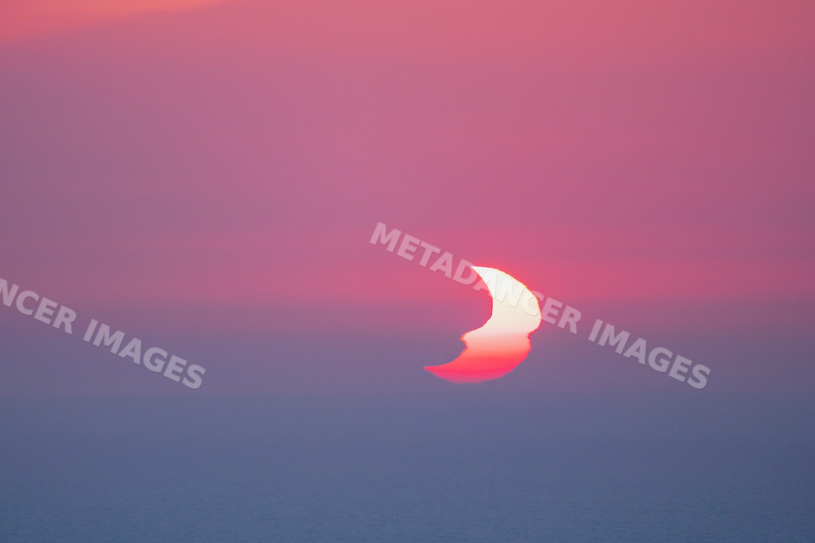Partially Eclipsed Sun setting over sea in valldemossa, Mallorca