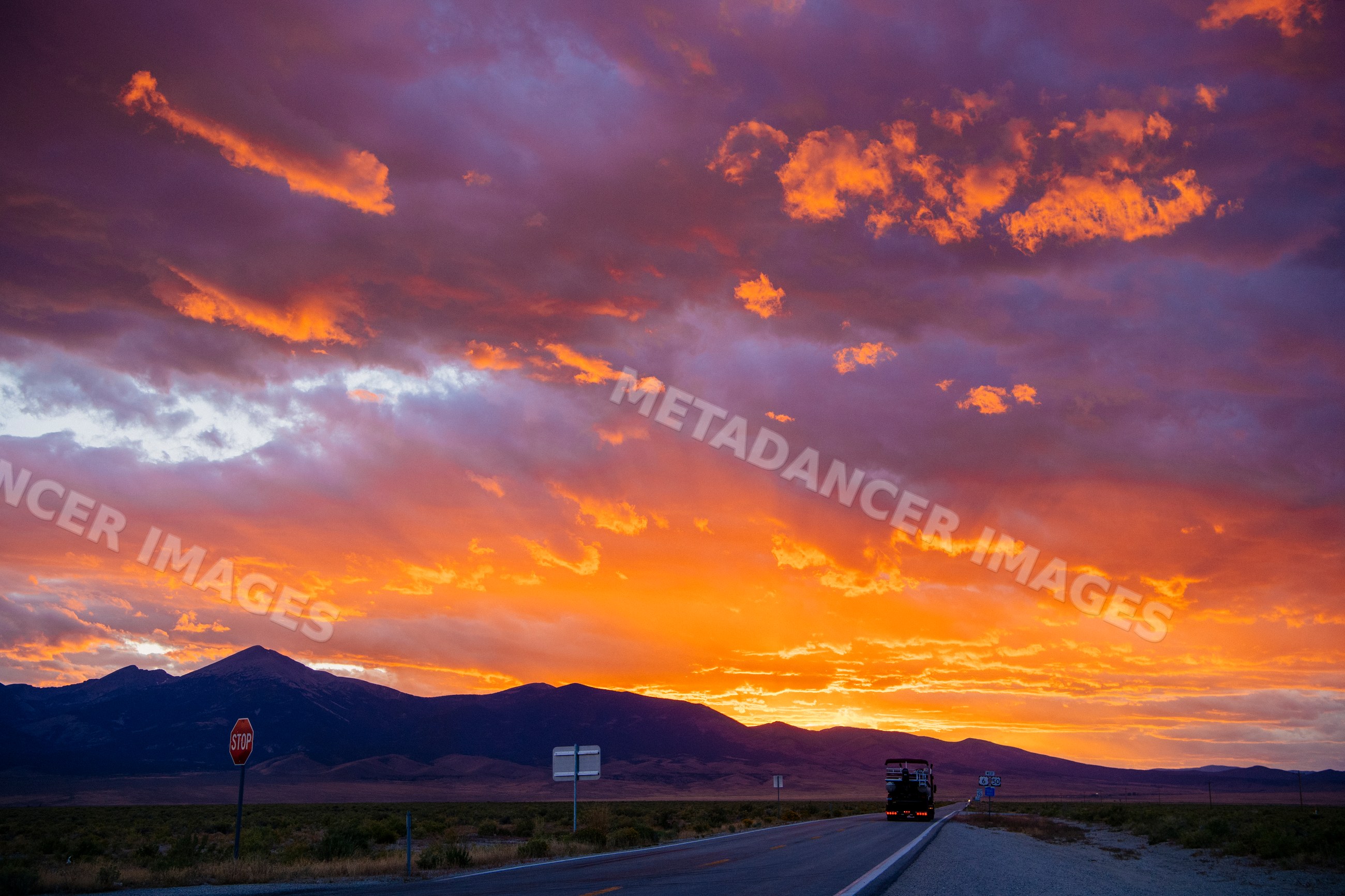 Sunset over Nevada mountain range with truck on desert highway