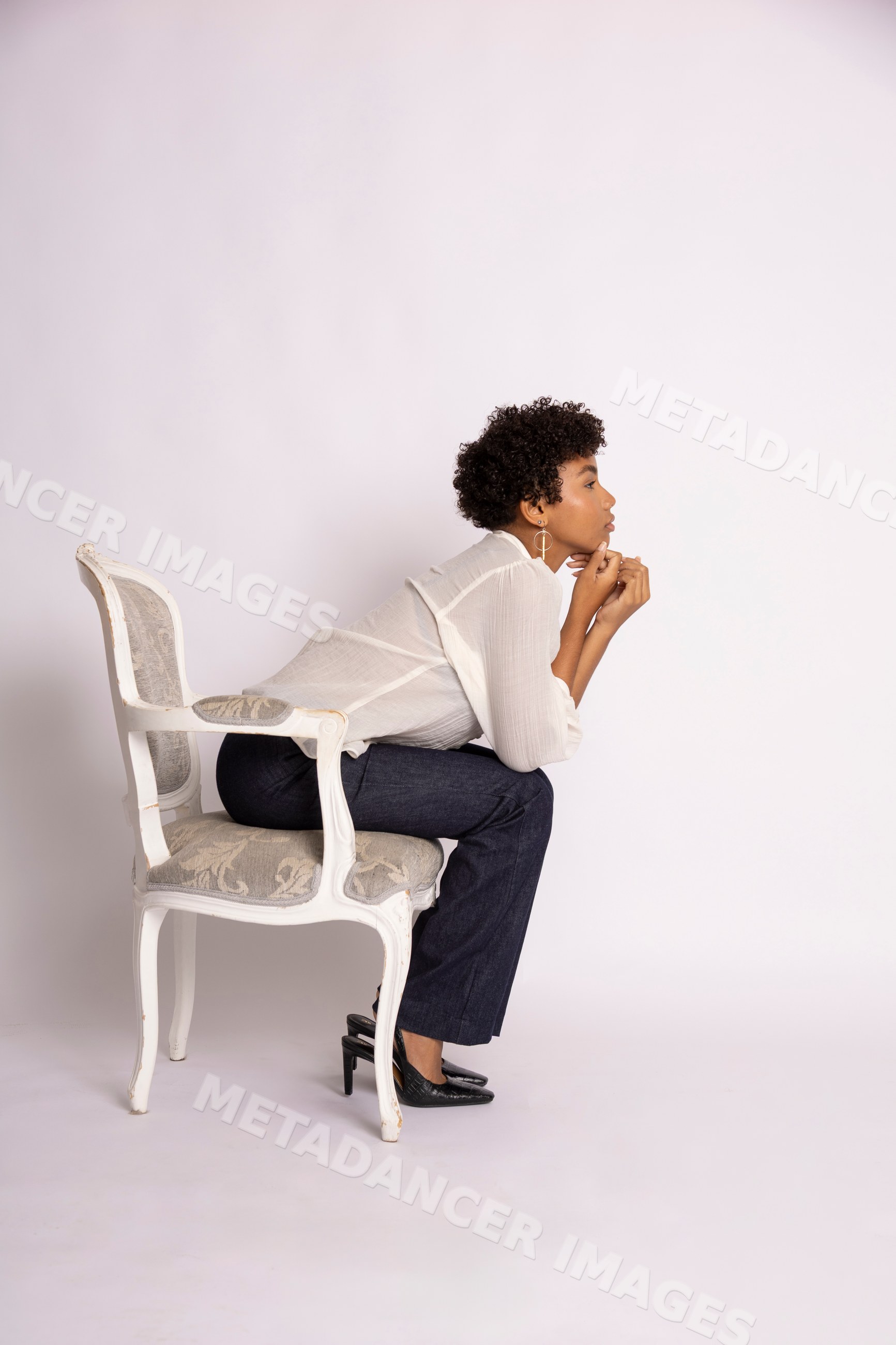 Hispanic woman sitting thoughtfully on white chair
