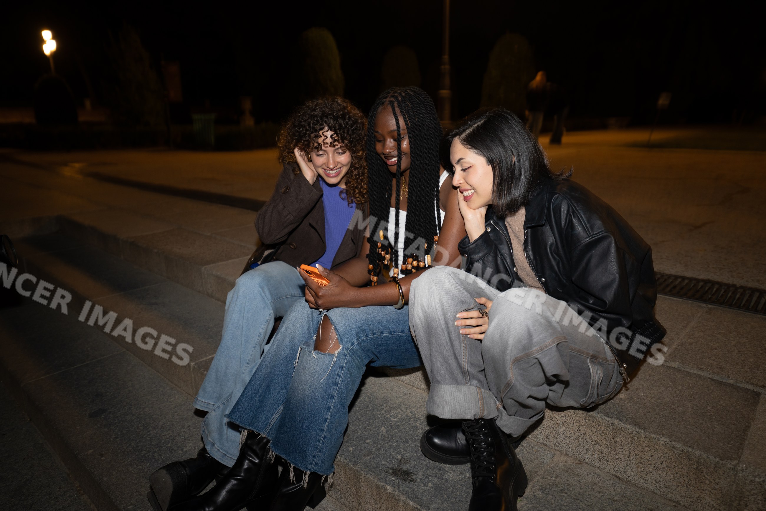Three Hispanic, white and Black women sitting on steps