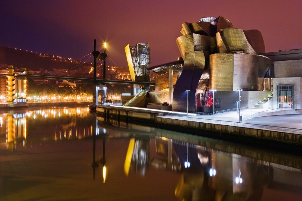 Guggenheim museum bilbao illuminated at night on riverfront