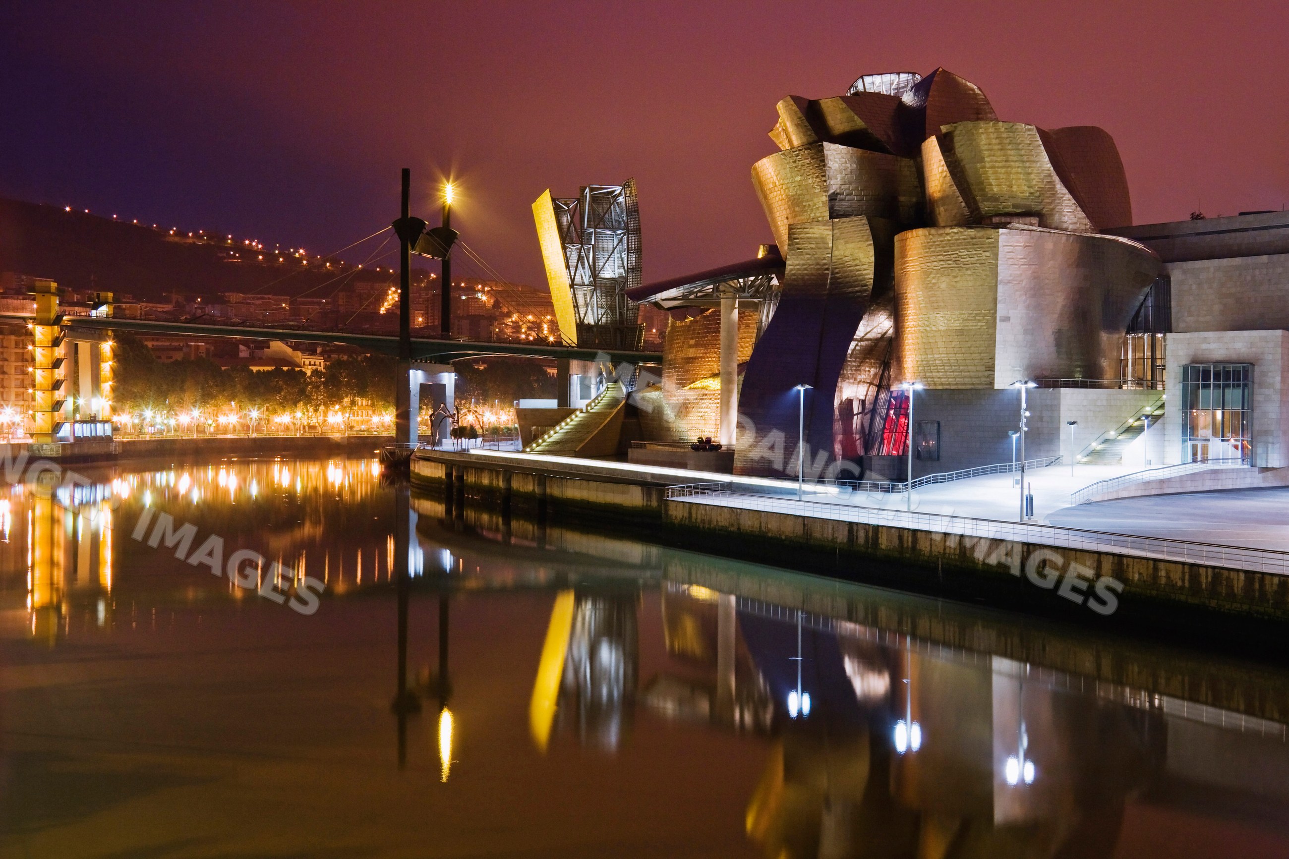 Guggenheim museum bilbao illuminated at night on riverfront