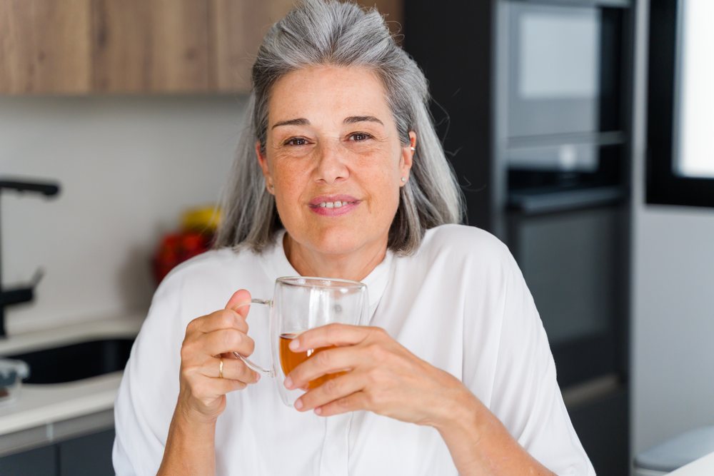 Mature white woman drinking tea in a kitchen interior in a kitchen