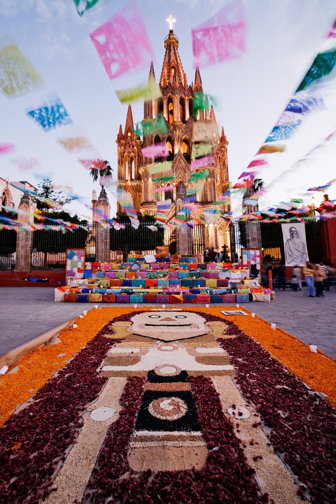 Altar decorated with flower petals and flags during day of the dead