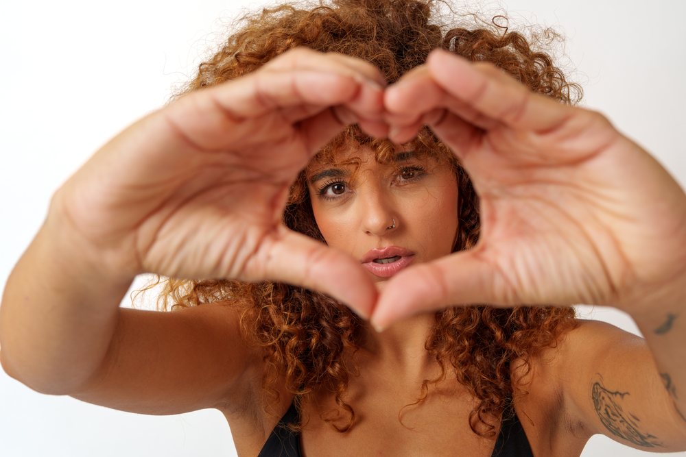 Hispanic woman making heart shape gesture with hands