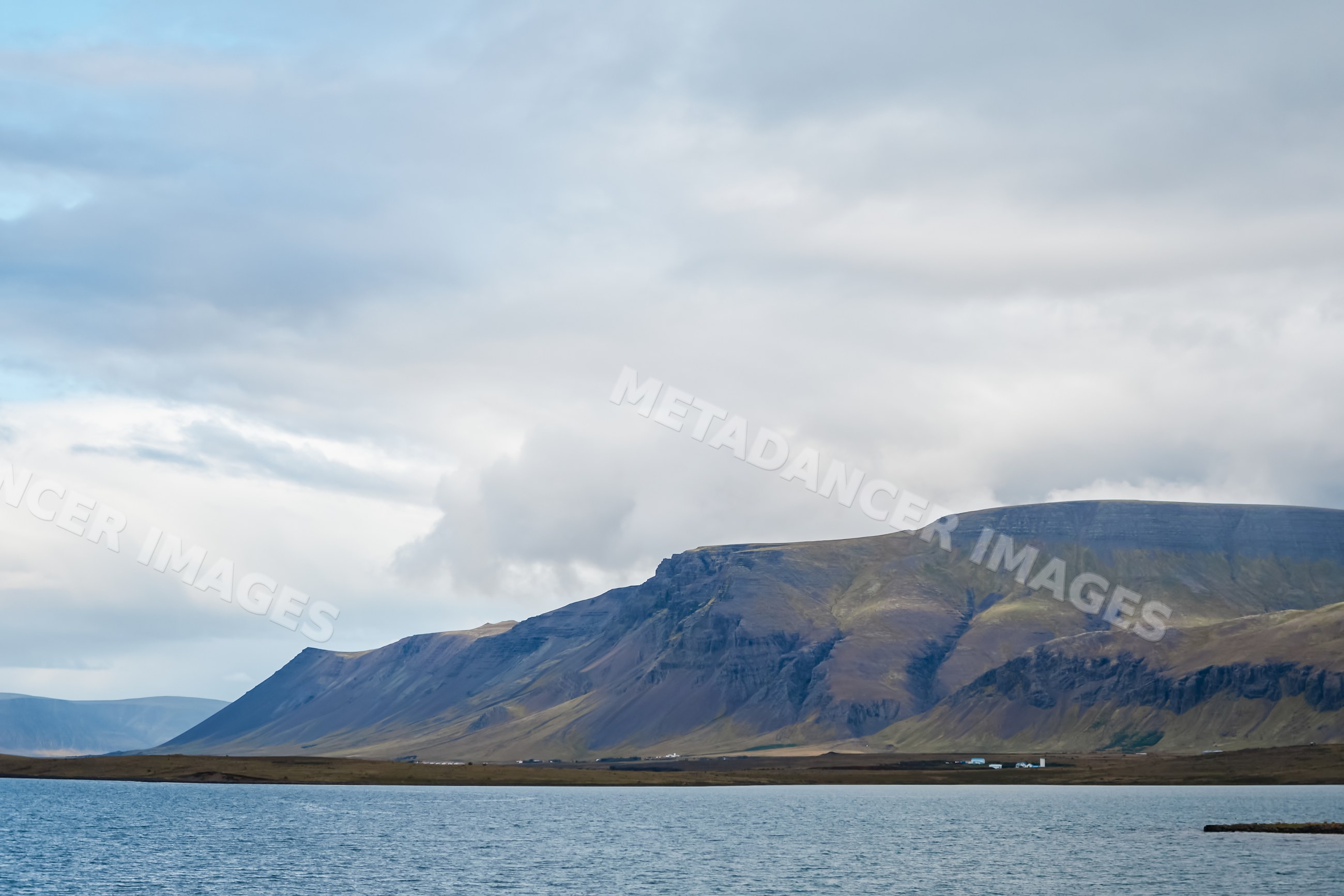 Mountain range overlooking a lake under a cloudy sky