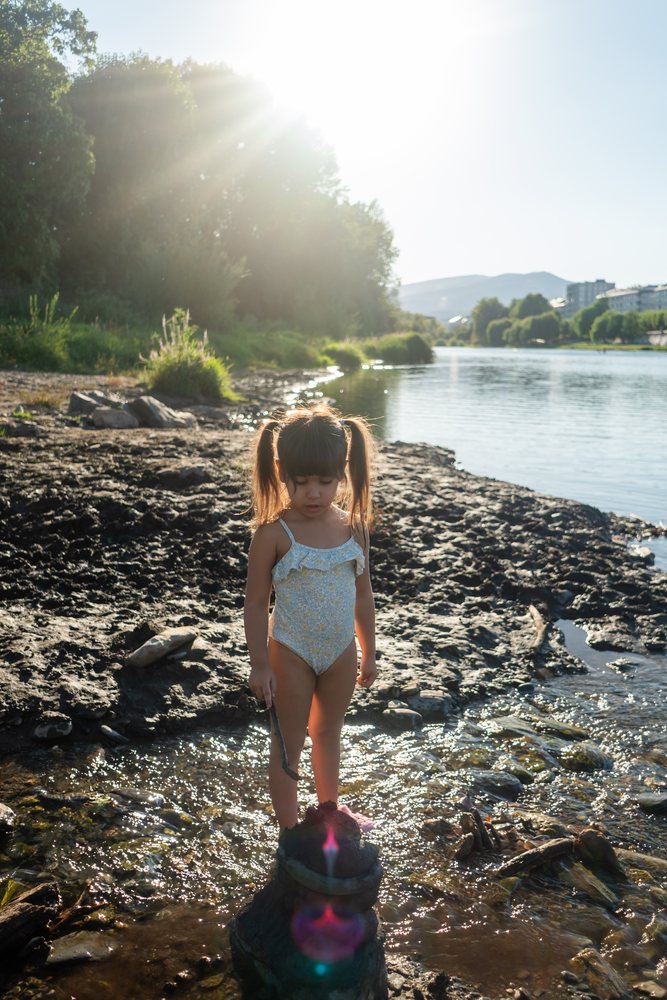 Young white girl playing by the riverbank in Spain on a sunny day
