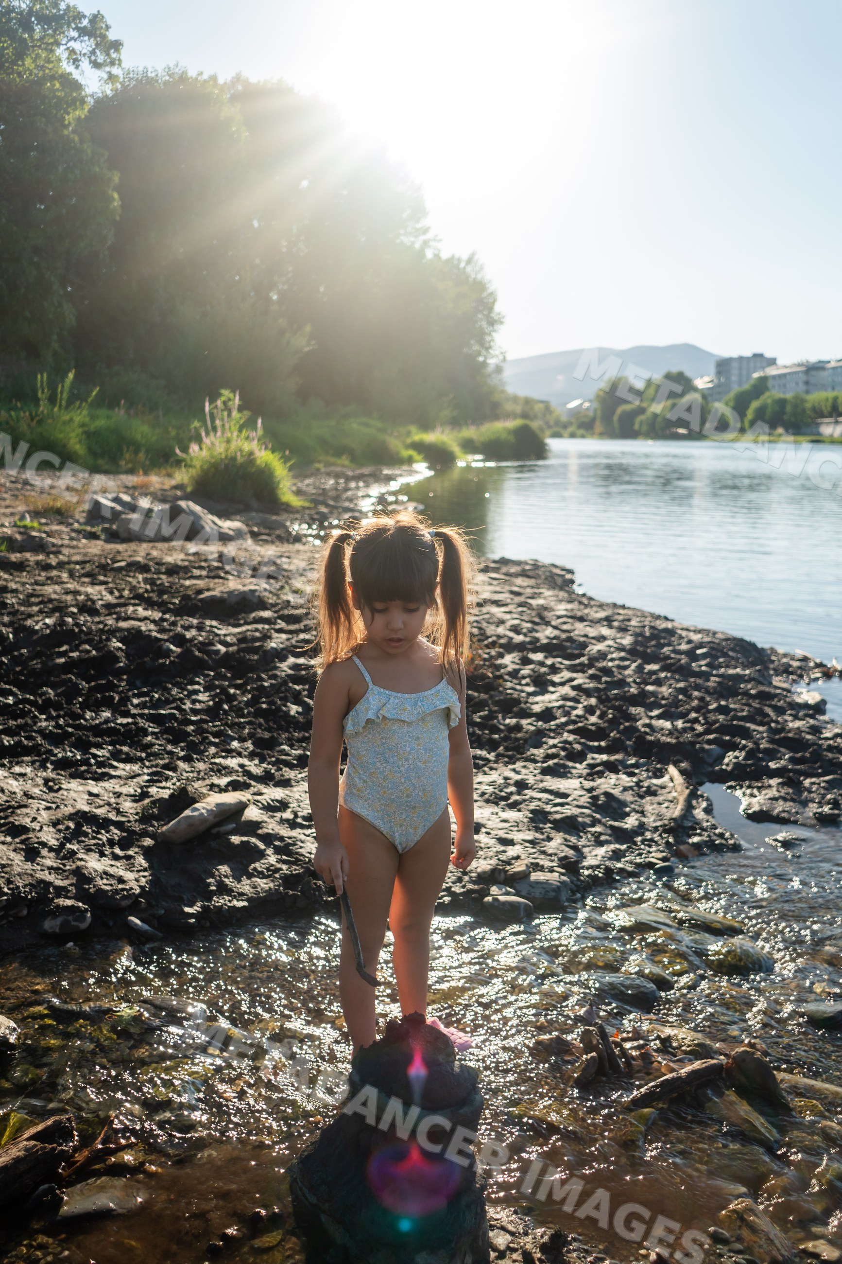 Young white girl playing by the riverbank in Spain on a sunny day