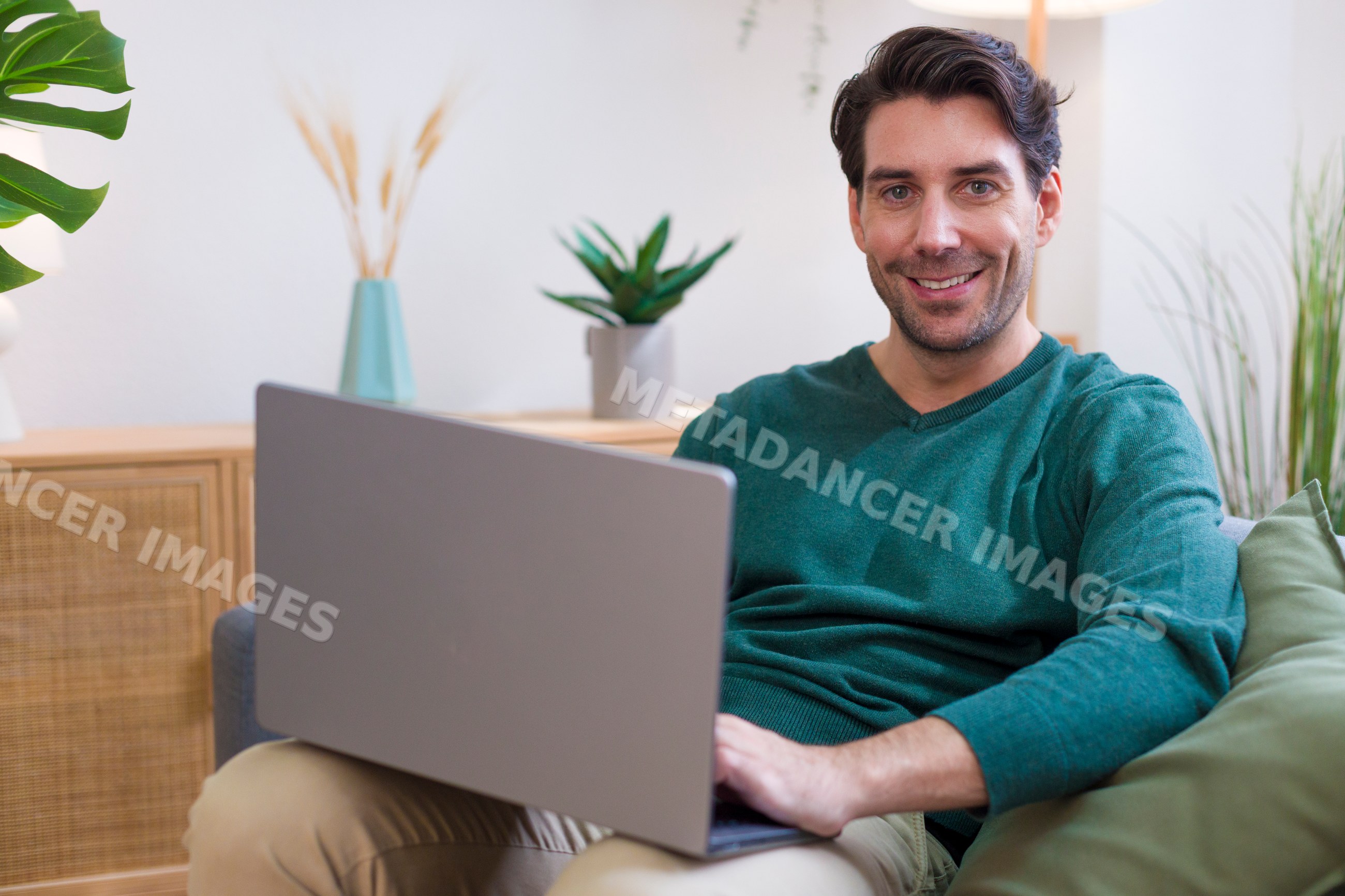 White man using laptop computer in cozy modern home environment