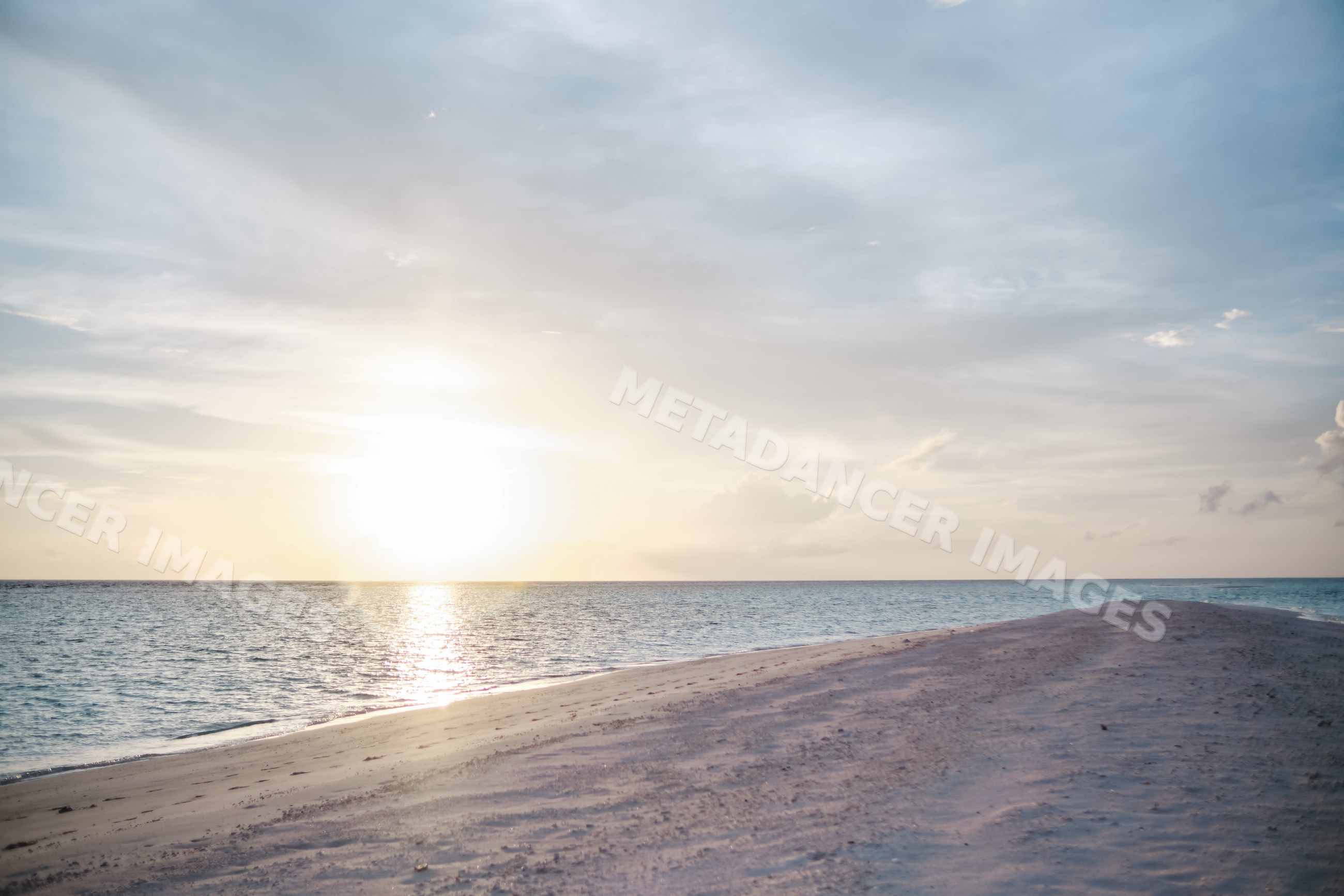 A serene sunset over a sandy beach and ocean shoreline in a beach